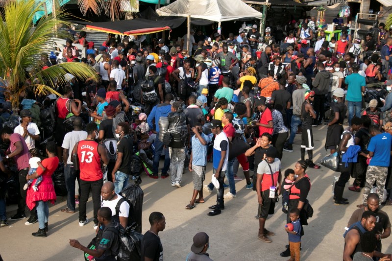 Migrants gather next to stores as they wait to cross into Panama to continue their journey toward the U.S., in Necocli