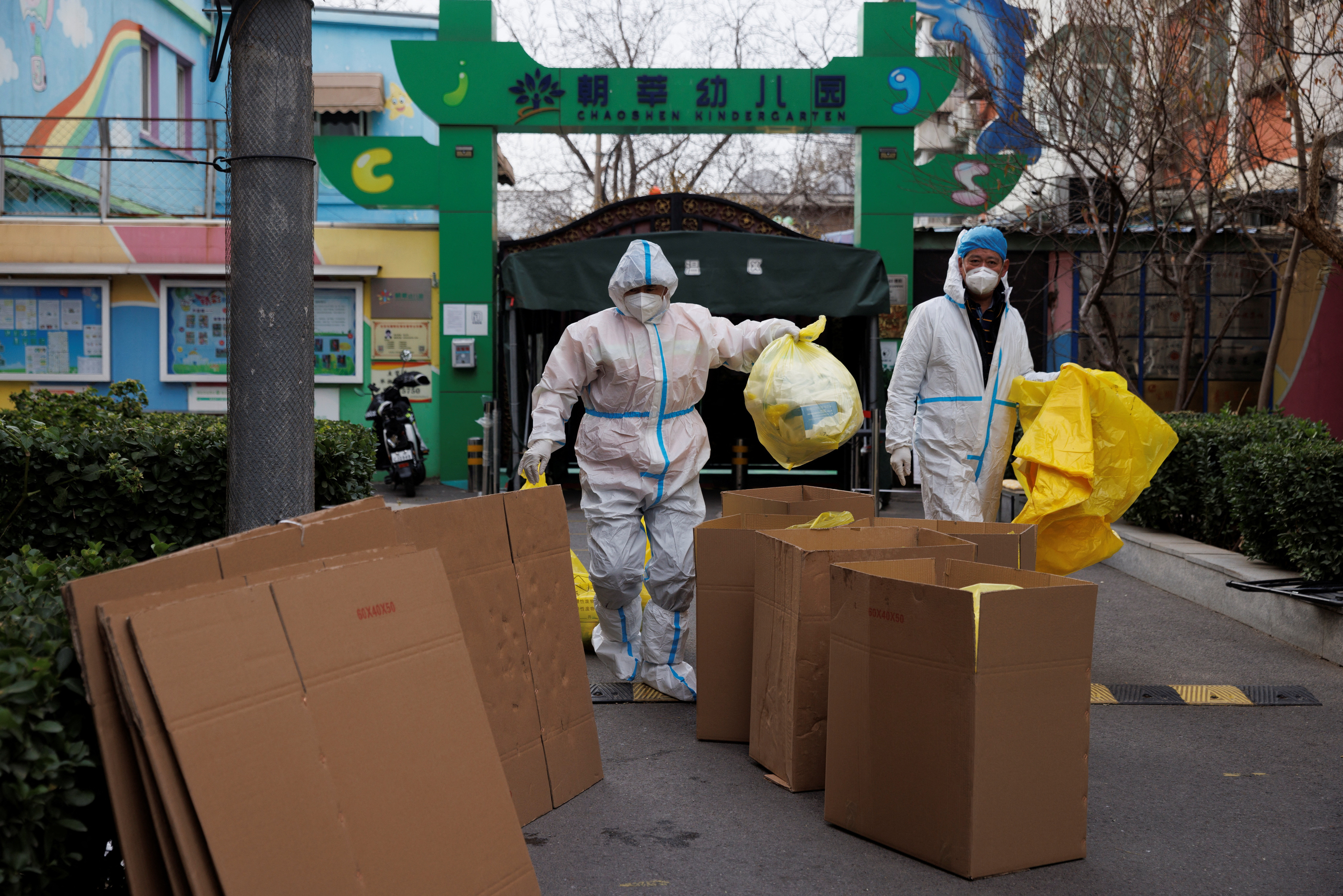Epidemic prevention workers in protective suits put medical waste into boxes in a residential compound as outbreaks of the coronavirus disease (COVID-19) continue in Beijing