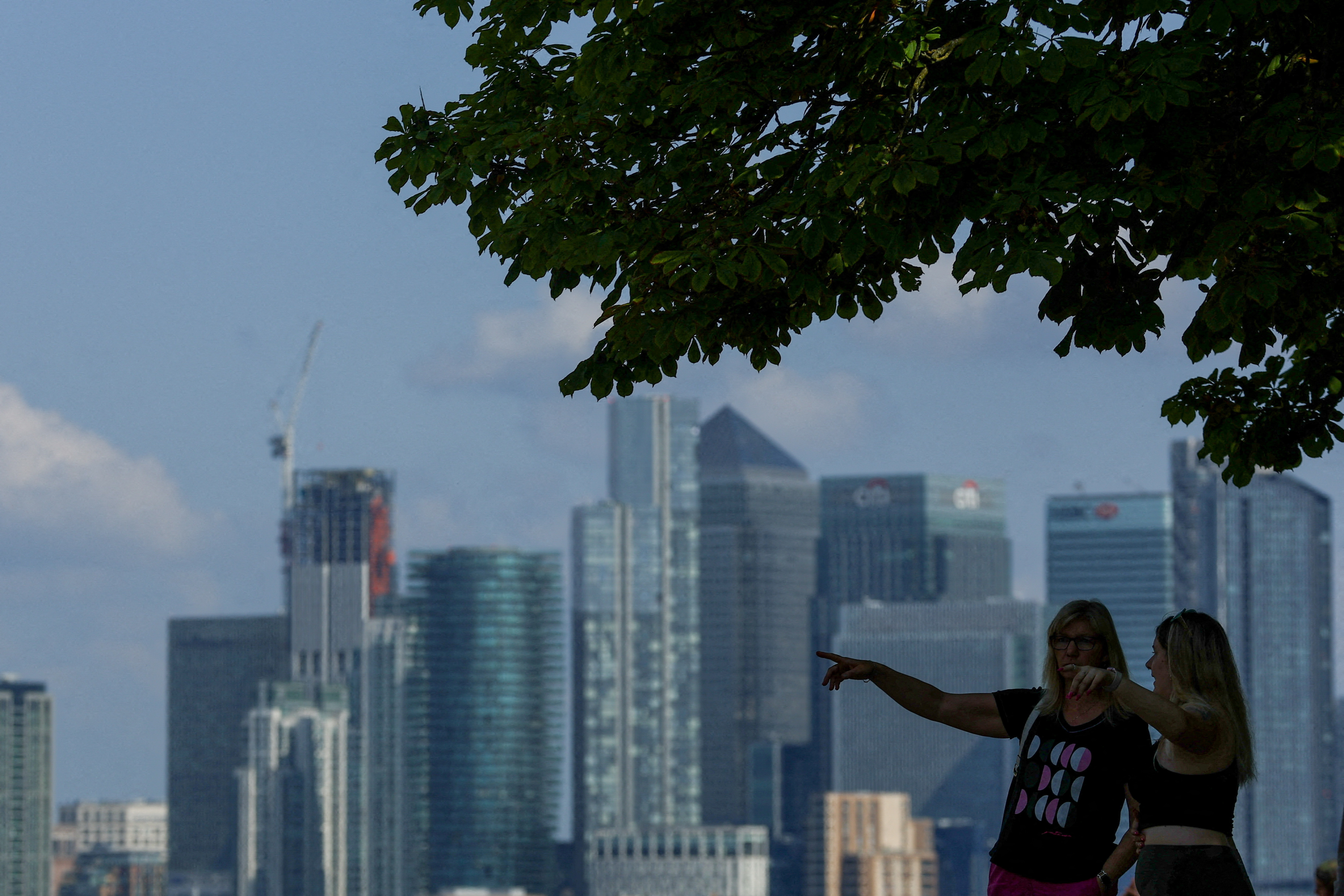 People look out from Greenwich Park, with Canary Wharf in the distance, in London