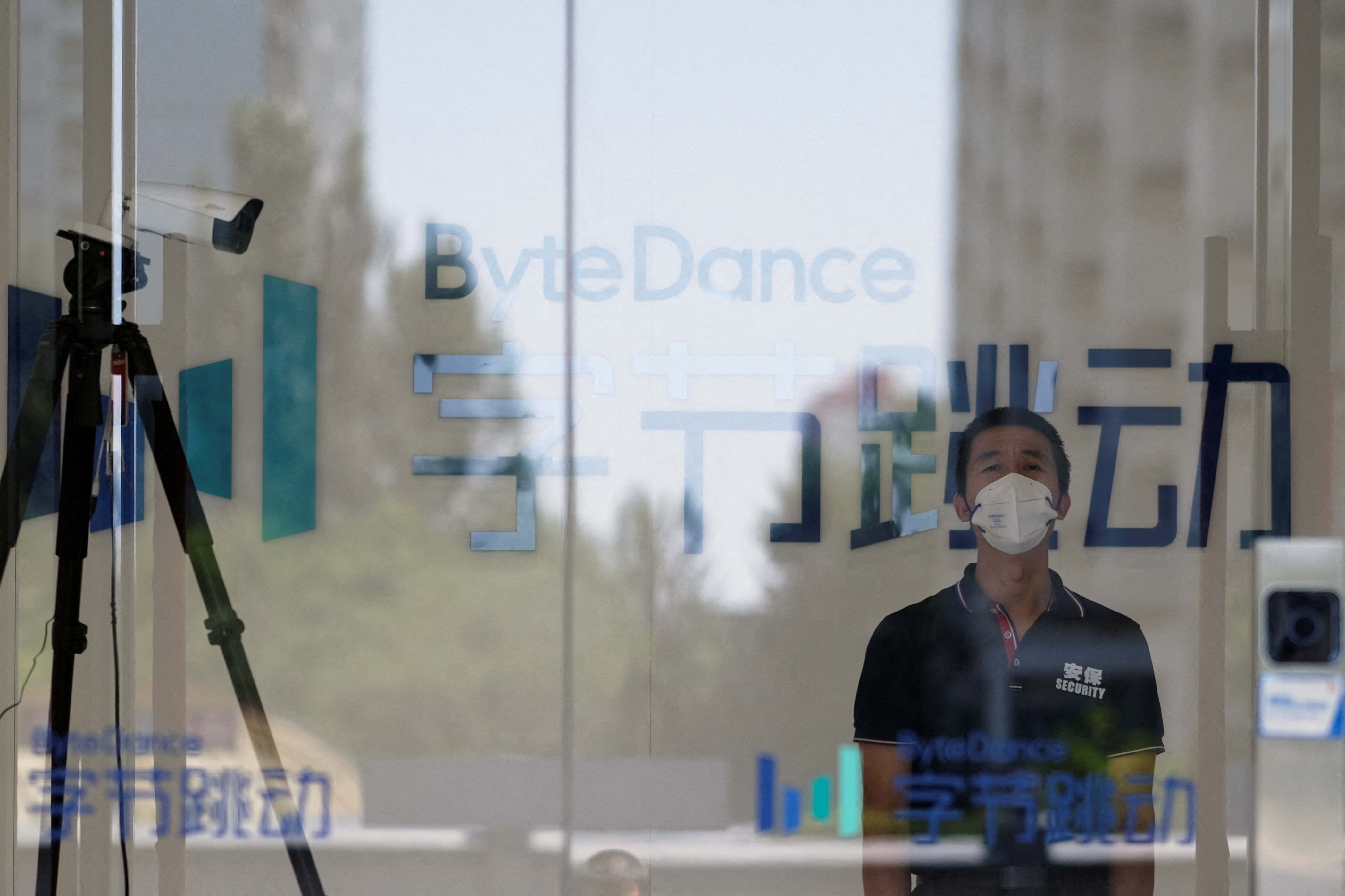 A security guard, wearing a face mask following the coronavirus disease (COVID-19) outbreak, stands near a surveillance camera at an office of Bytedance. Beijing, China July 7, 2020.  REUTERS/Thomas Suen/File Photo