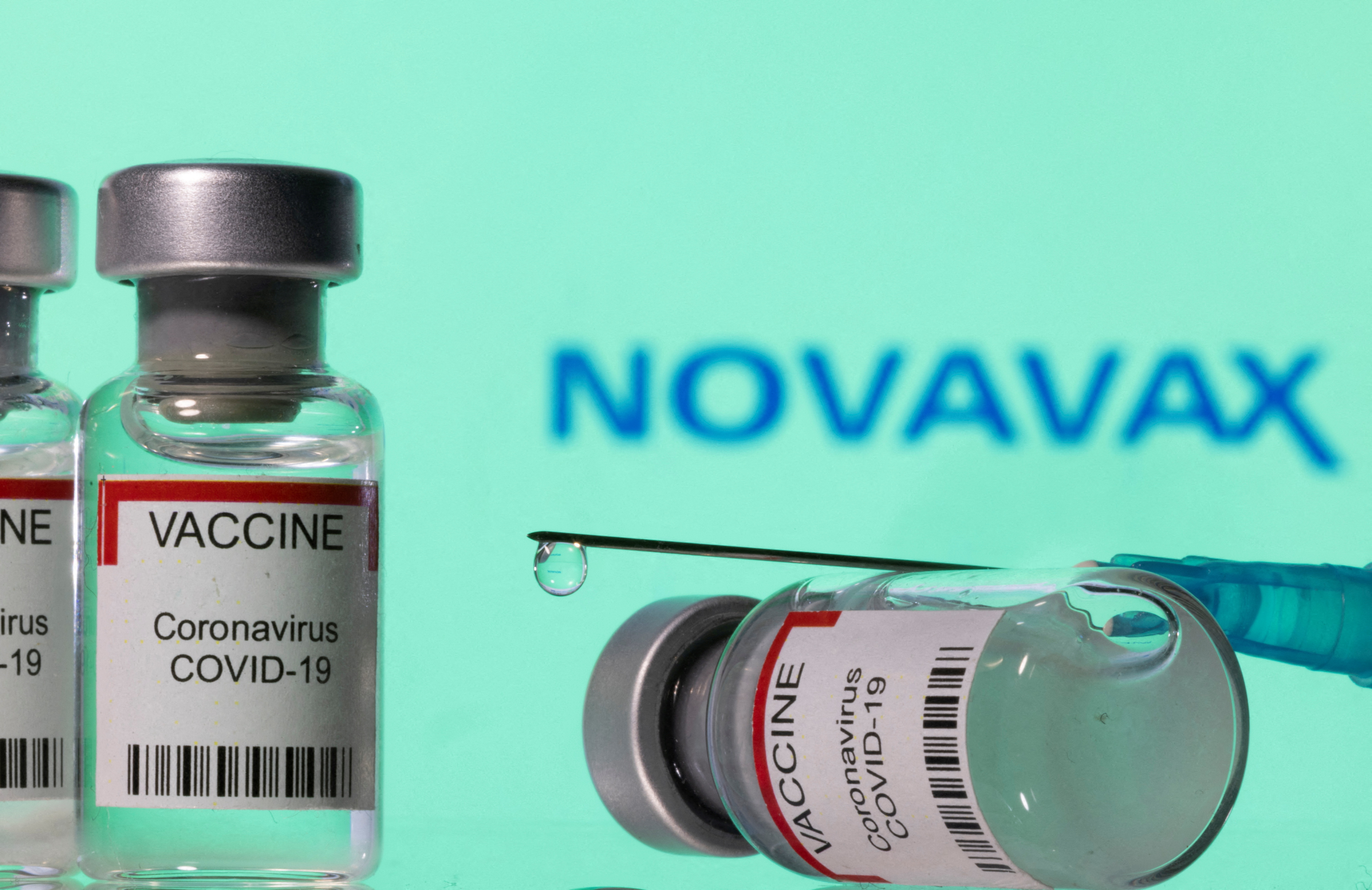 Illustration shows vials labelled "VACCINE Coronavirus COVID-19" and a syringe in front of a displayed Novavax logo