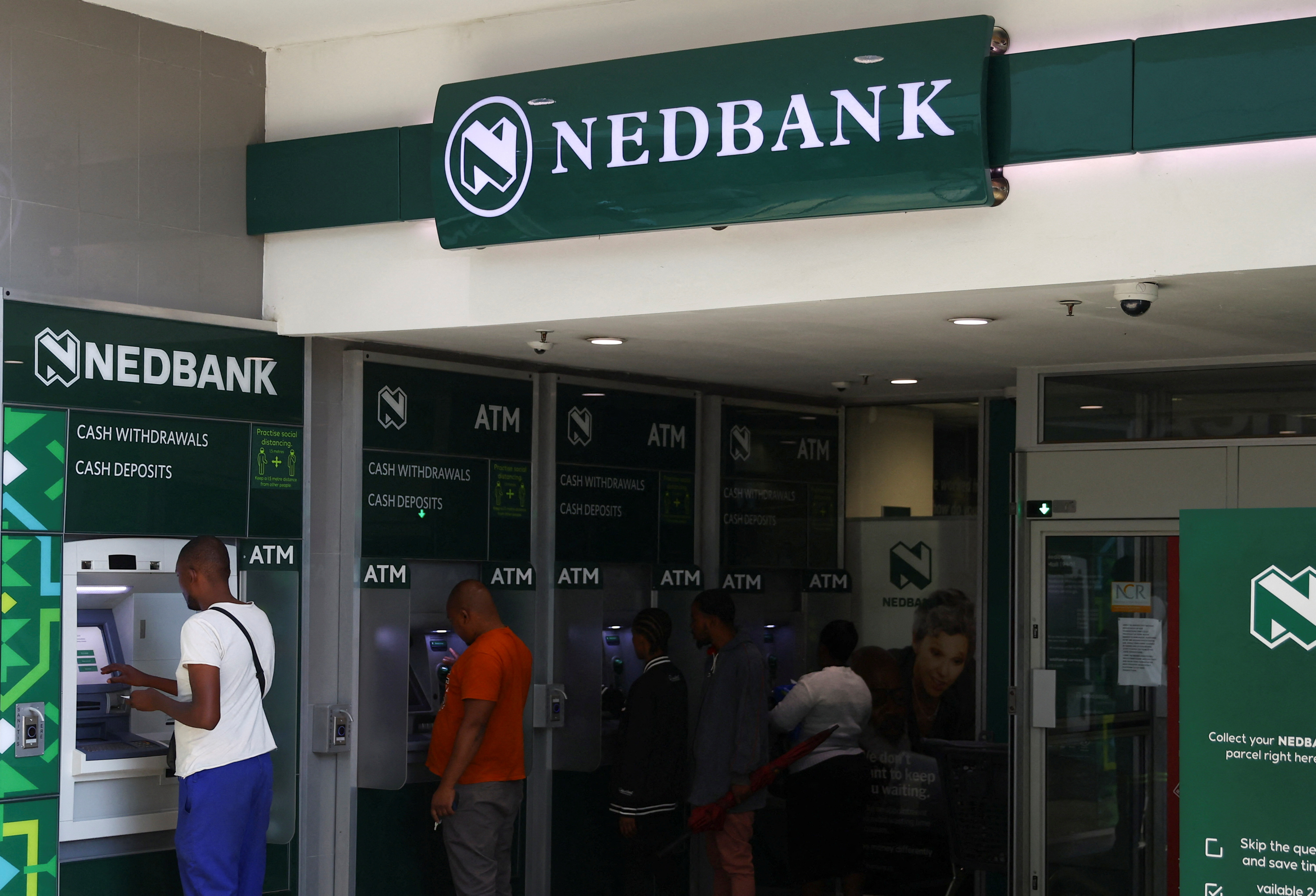 Customers perform transactions on Nedbank automated teller machine