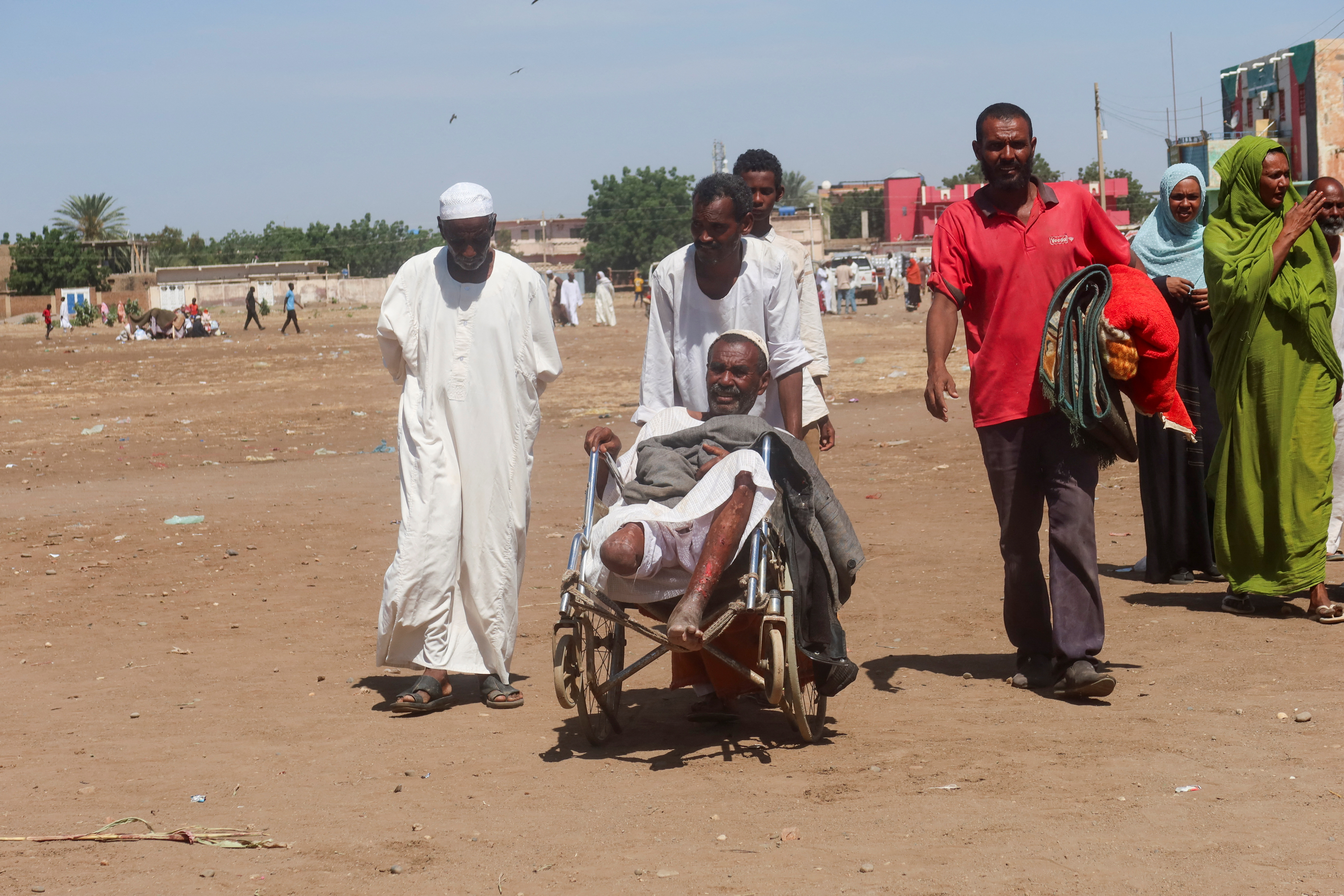 A man helps Hashim Basheer, a Sudanese man with a disability, displaced from Gezira state due to RSF violence, in New Halfa