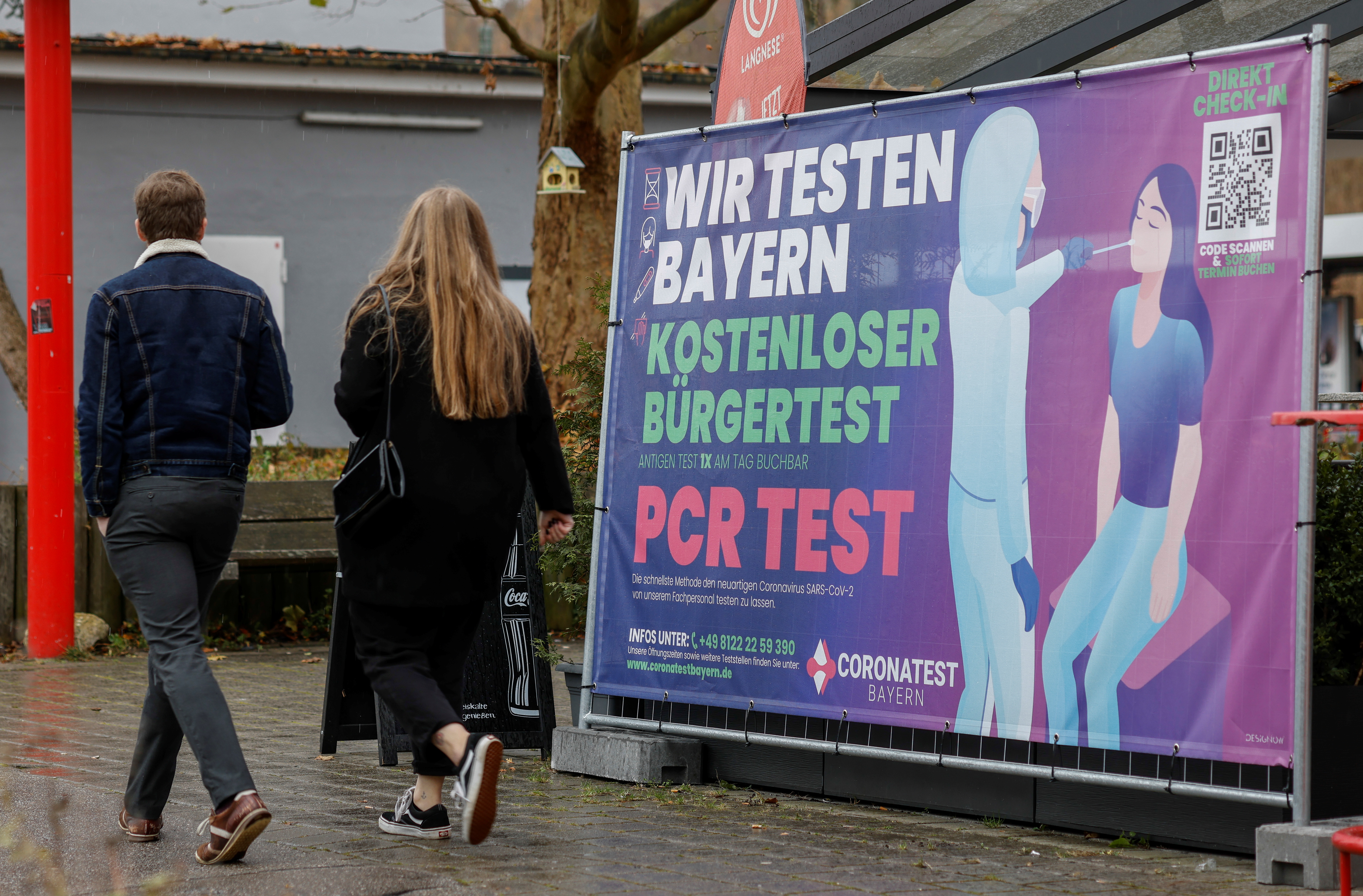 People walk past a sign of a coronavirus disease (COVID-19) test centre amid the COVID-19 pandemic in Furstenfeldbruck