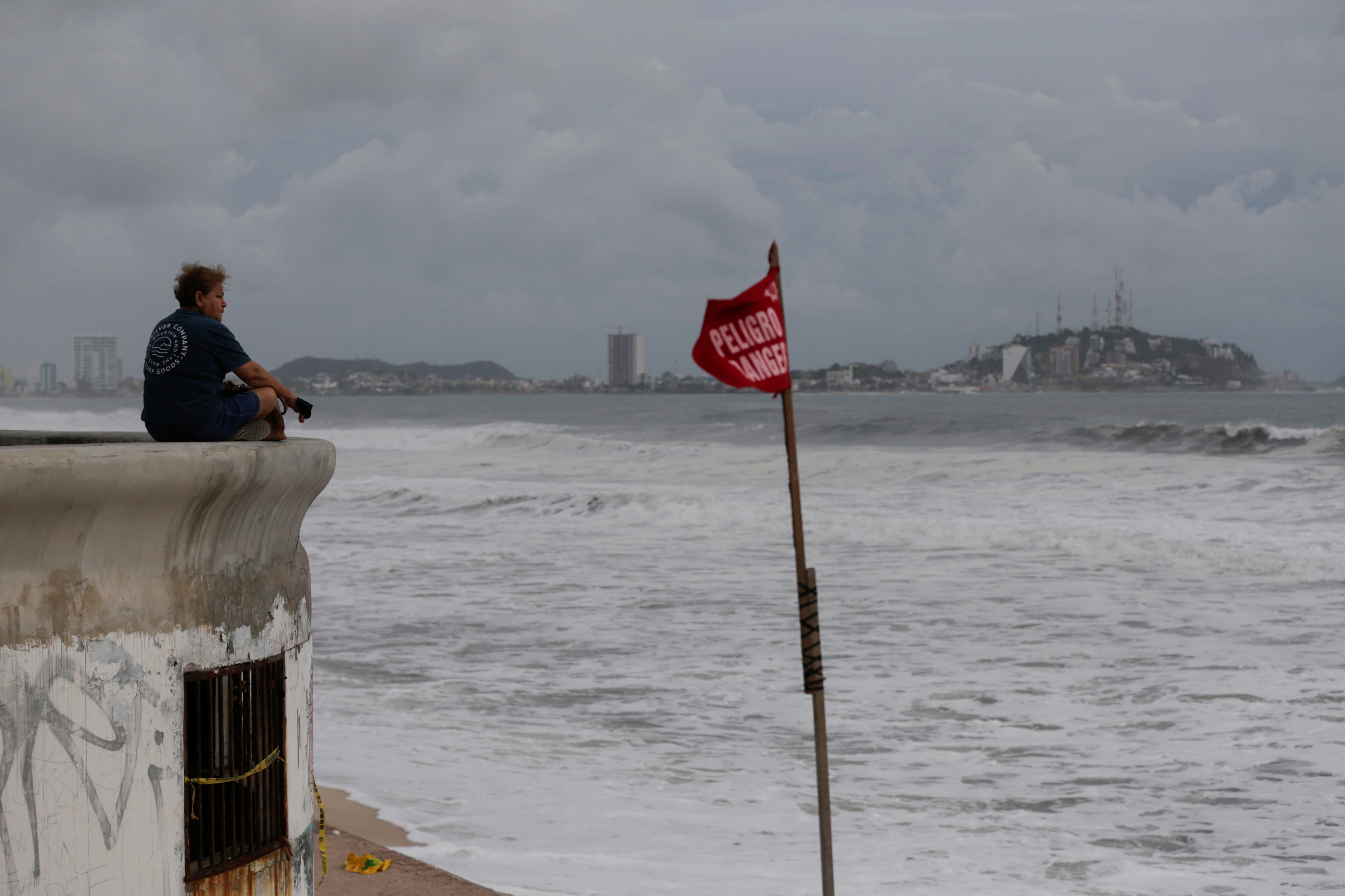 Woman watches the sea near a red flag warning of dangerous conditions at a closed beach as storm Pamela approaches the Pacific coast resort, in Mazatlan