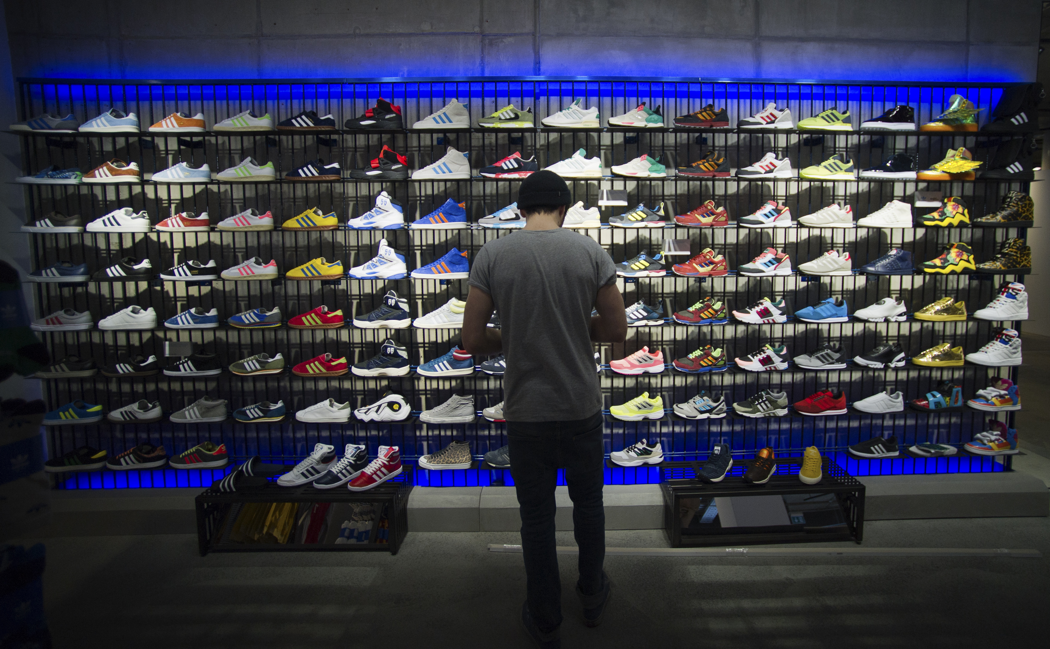 A man stands in front of a rack with Adidas Original shoes before the opening at the new Adidas Originals store in Berlin