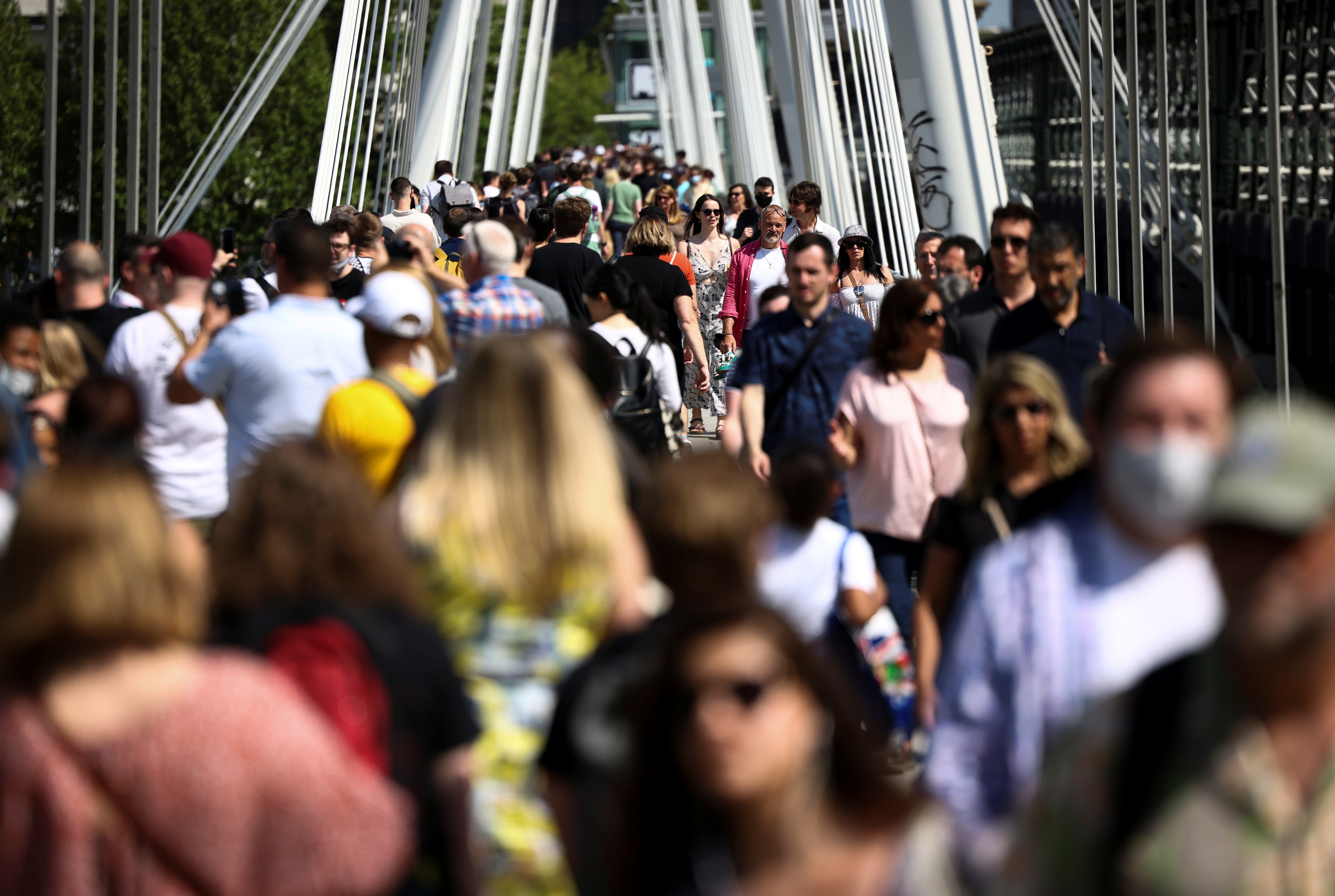 People walk across Millennium Bridge during sunny weather, amid the coronavirus disease (COVID-19) outbreak, in London