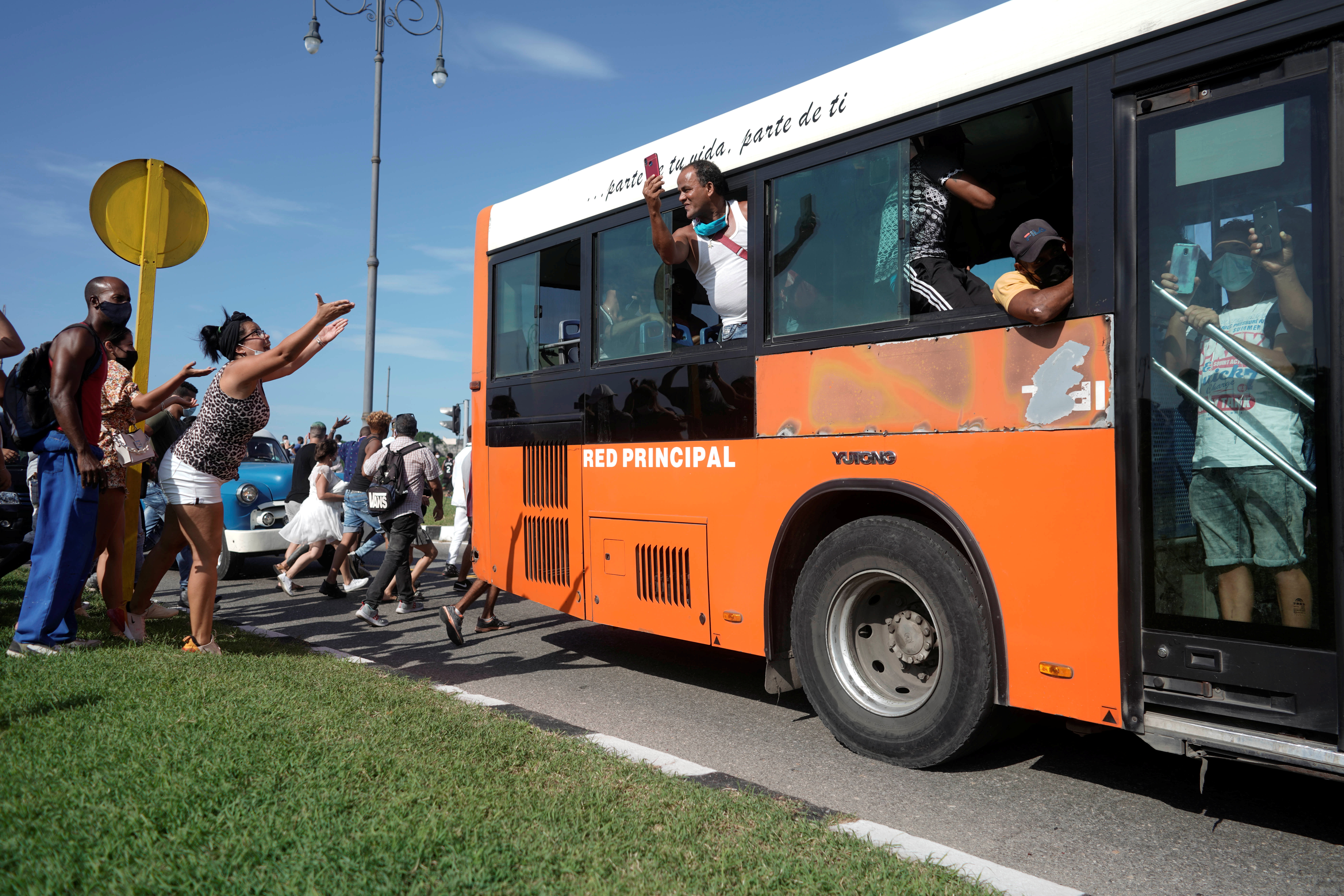 People ask passengers of a bus to join them during a during a protest against and in support of the government,  in Havana