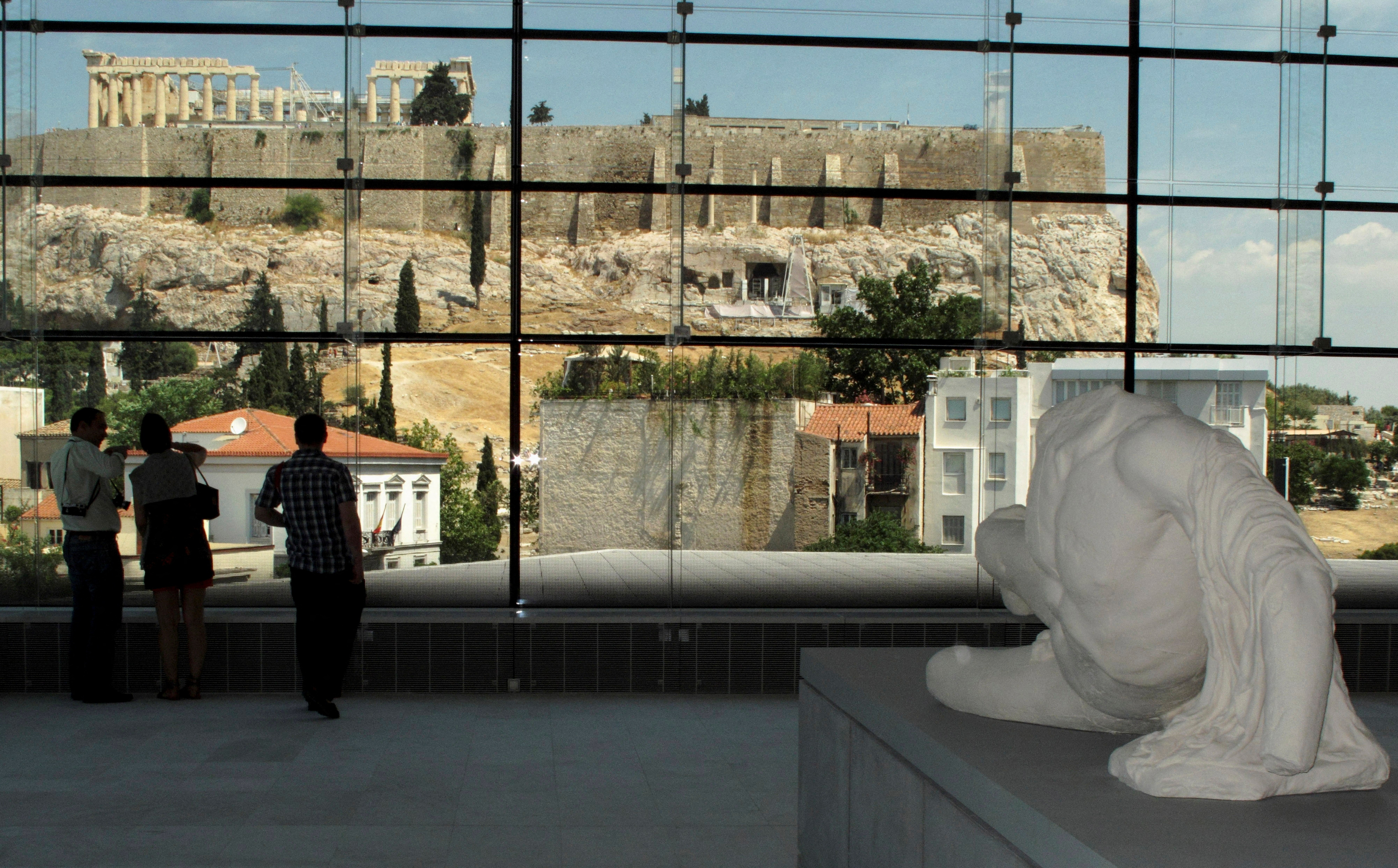 Visitors look at the temple of the Parthenon from inside the new Acropolis museum in Athens