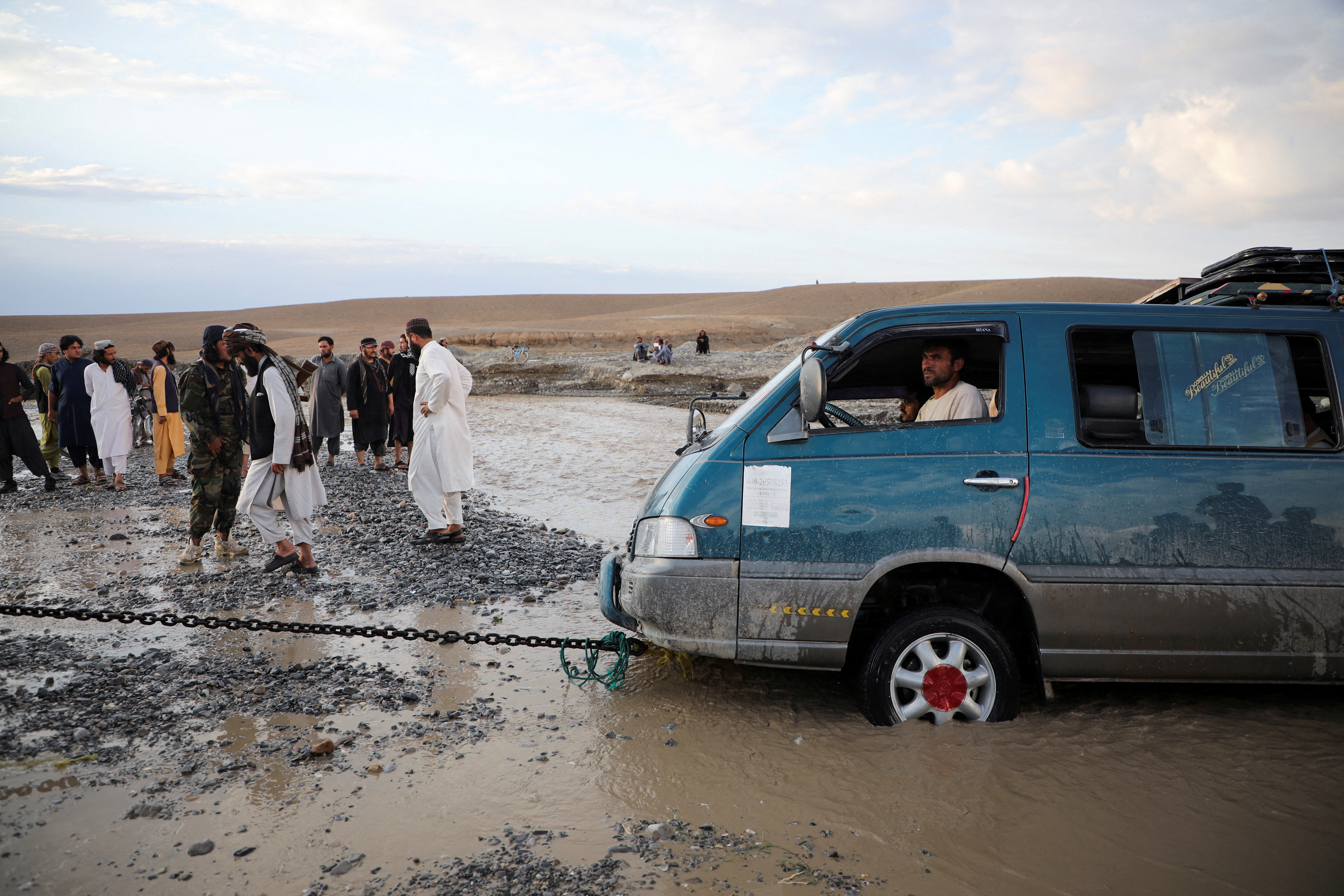 A minivan is being towed out of the flood water in the Khushi district of Logar