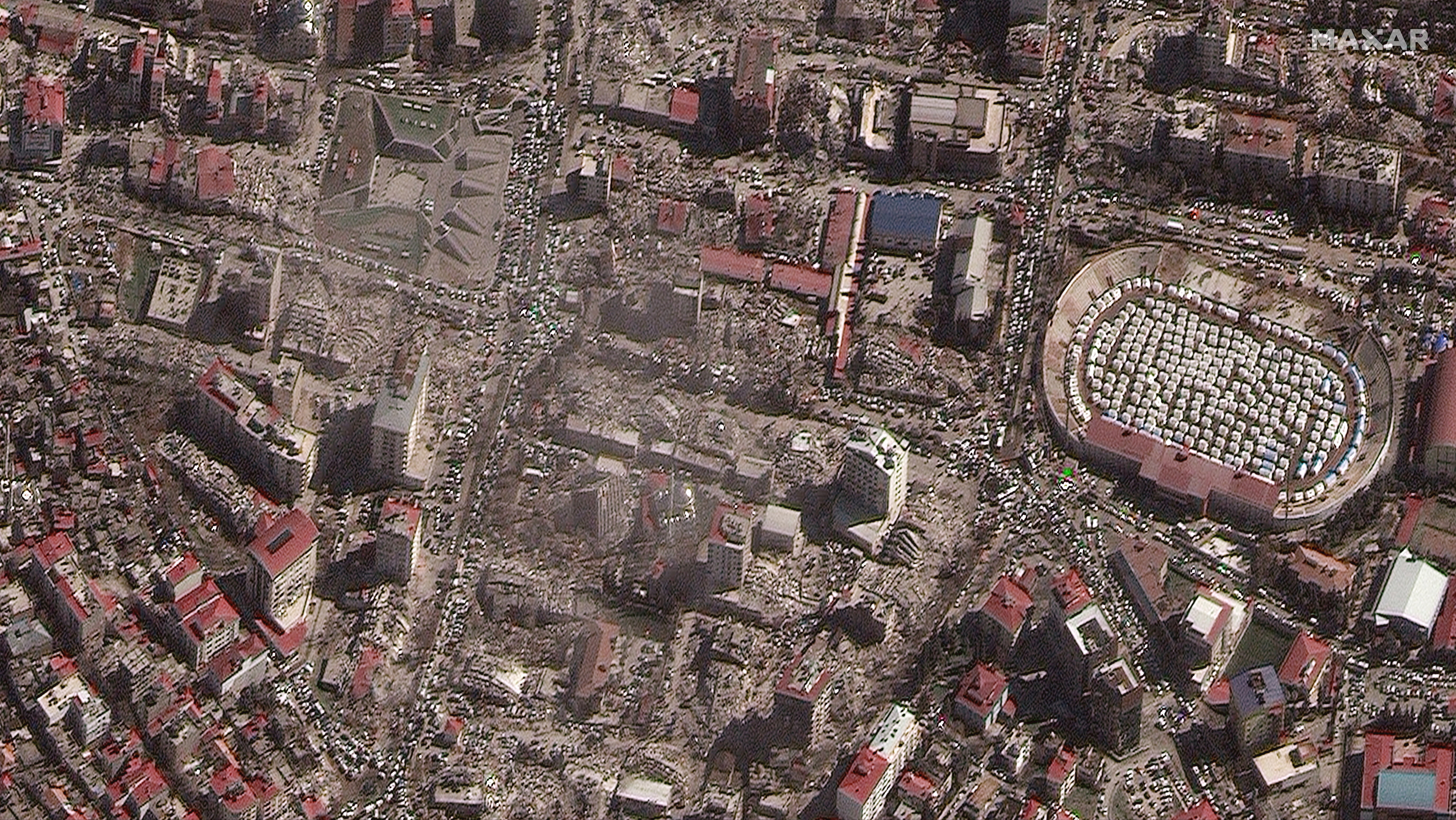 A satellite image shows destroyed buildings and emergency shelters in a stadium after an earthquake in Kahramanmaras