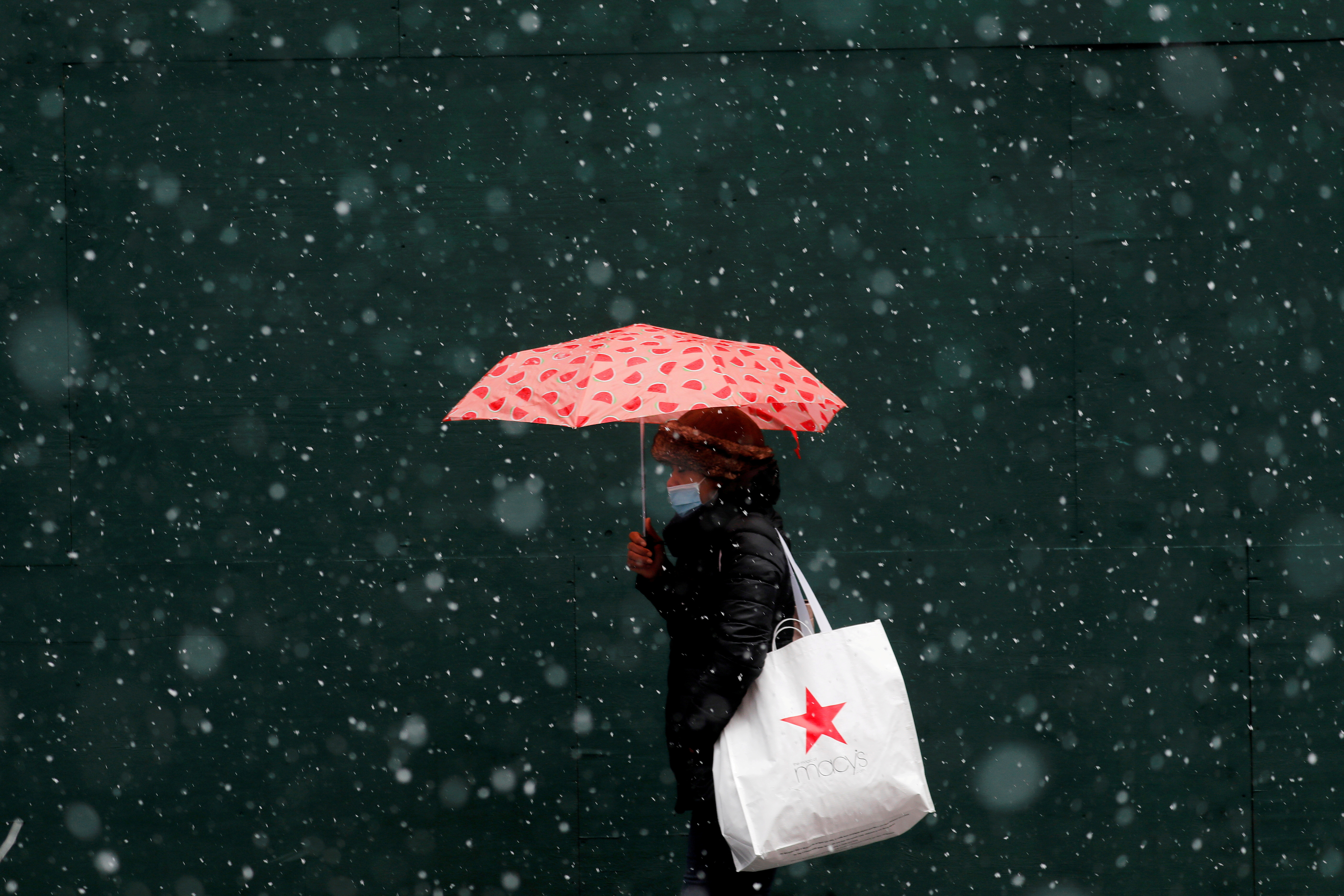 Una mujer que lleva una bolsa de Macy's camina sobre la nieve que cae mientras una tormenta de invierno se mueve hacia el noreste de los Estados Unidos, en Nueva York