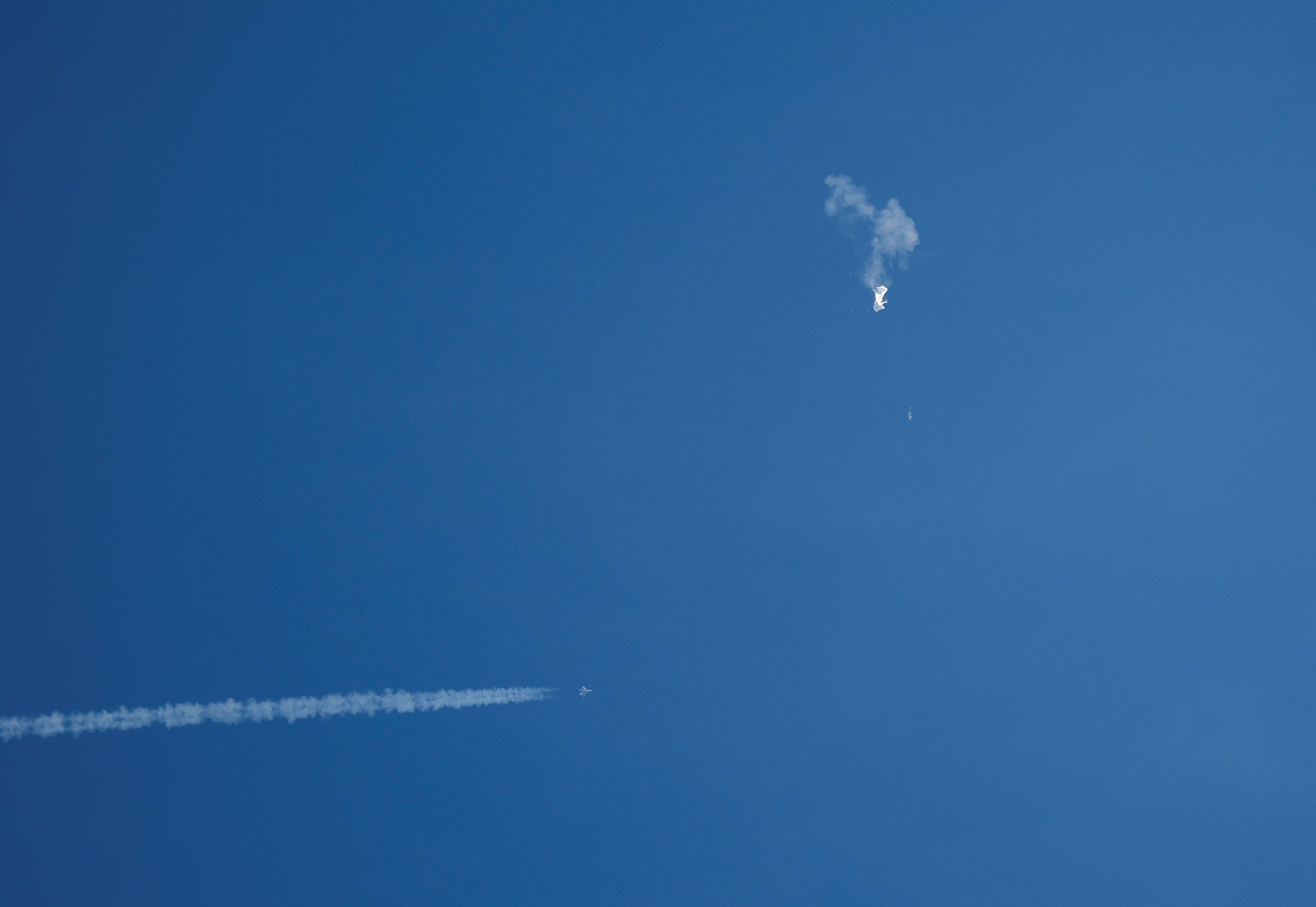 A jet flies by a suspected Chinese spy balloon after shooting it down off the coast in Surfside Beach