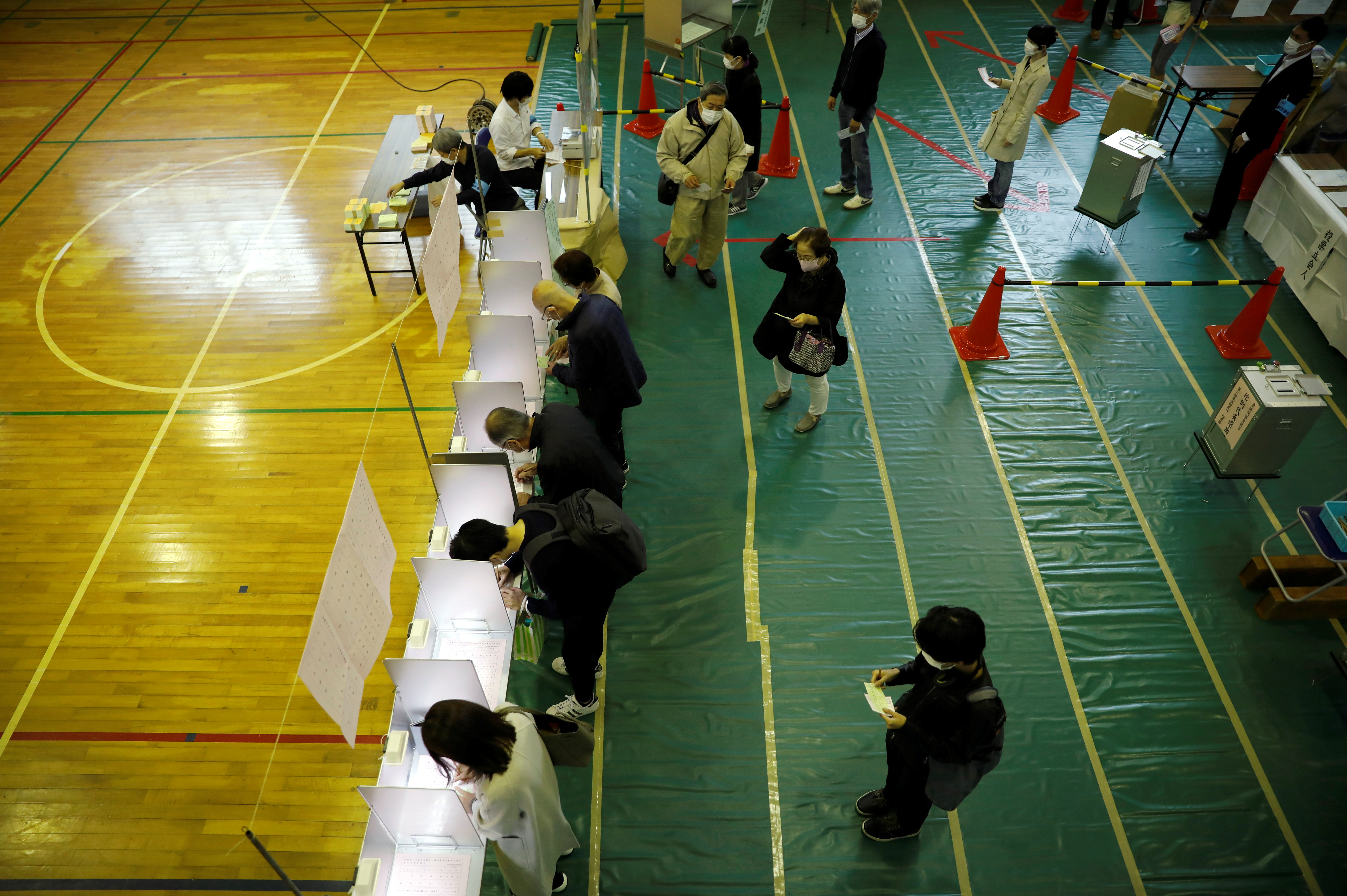 A voter casts a ballot in the lower house election at a polling station, amid the coronavirus disease (COVID-19) pandemic, in Tokyo