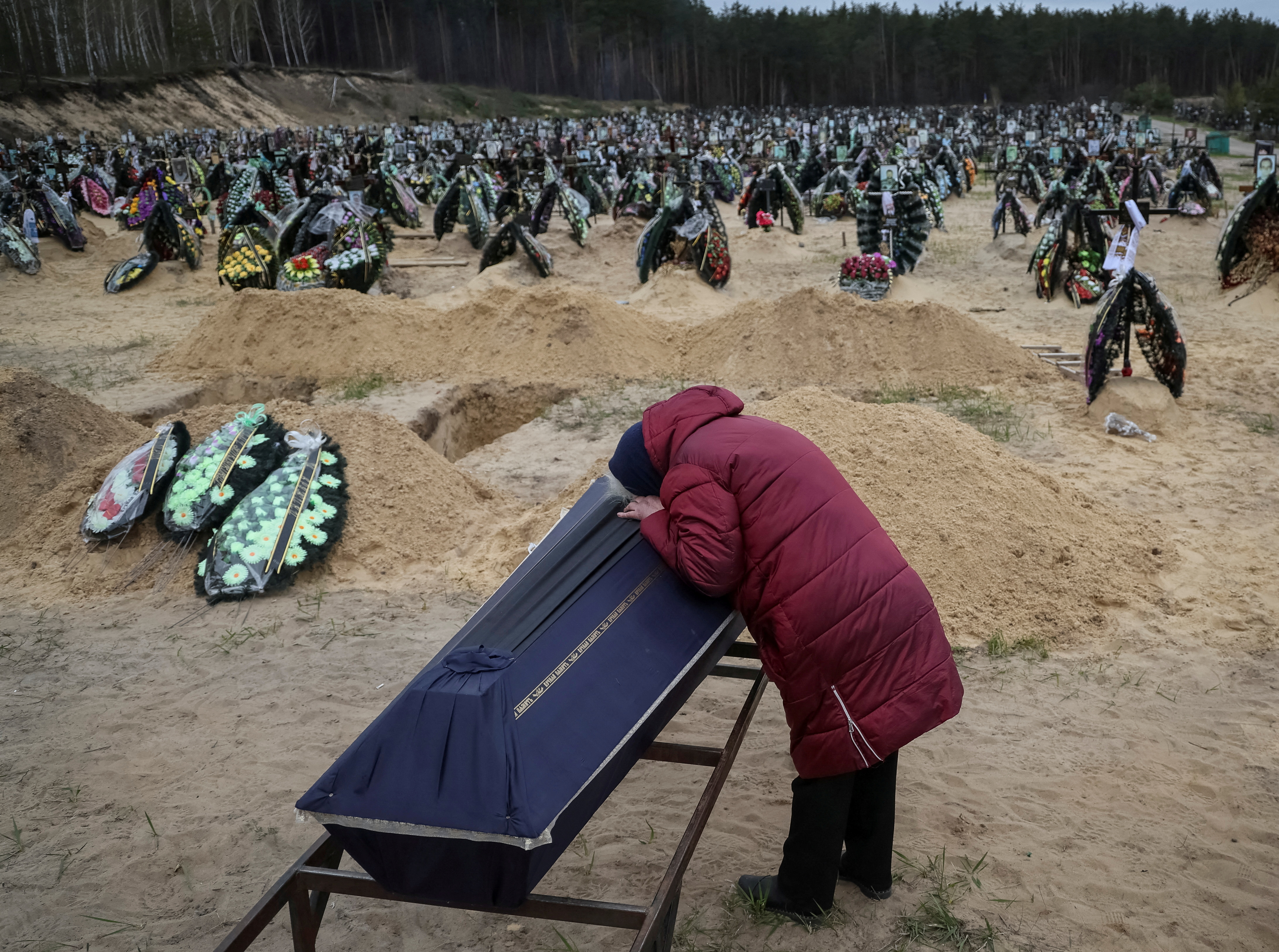 A woman reacts during a funeral of her relative, who died during the shelling by Russian troops, at the cemetery in Irpin