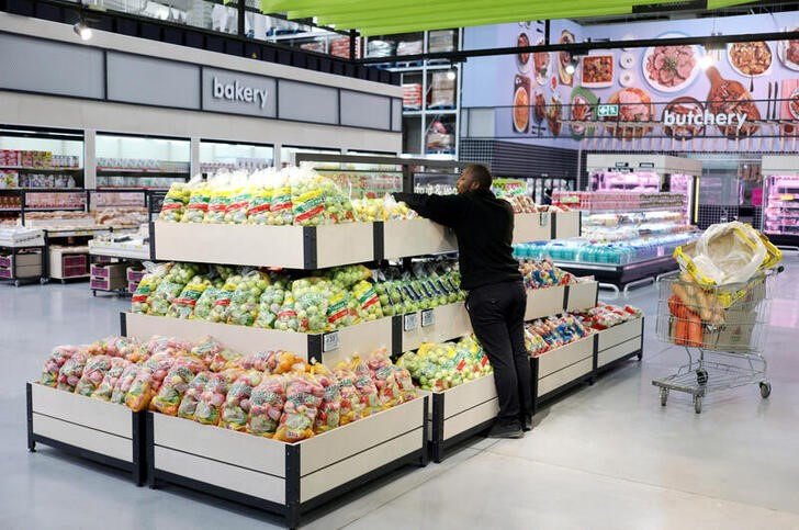 A worker arranges fruits on a shelf at Makro Store Riversands of South African retailer Massmart in Midrand