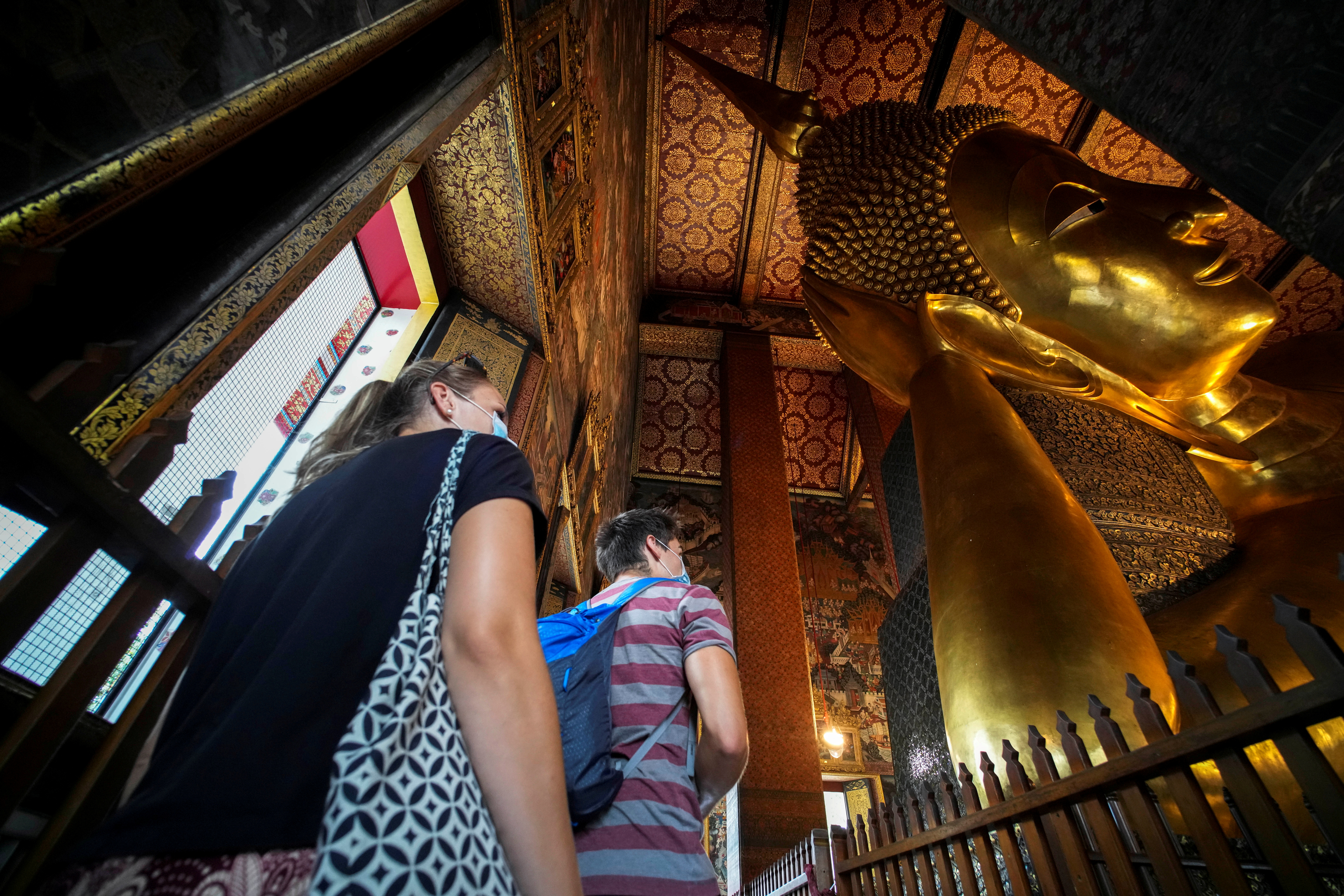 Foreign tourists are seen next to the Reclining Buddha at Wat Pho, a day after country's reopening campaign which is a part of the government's plan to jump start the pandemic-hit tourism sector in Bangkok