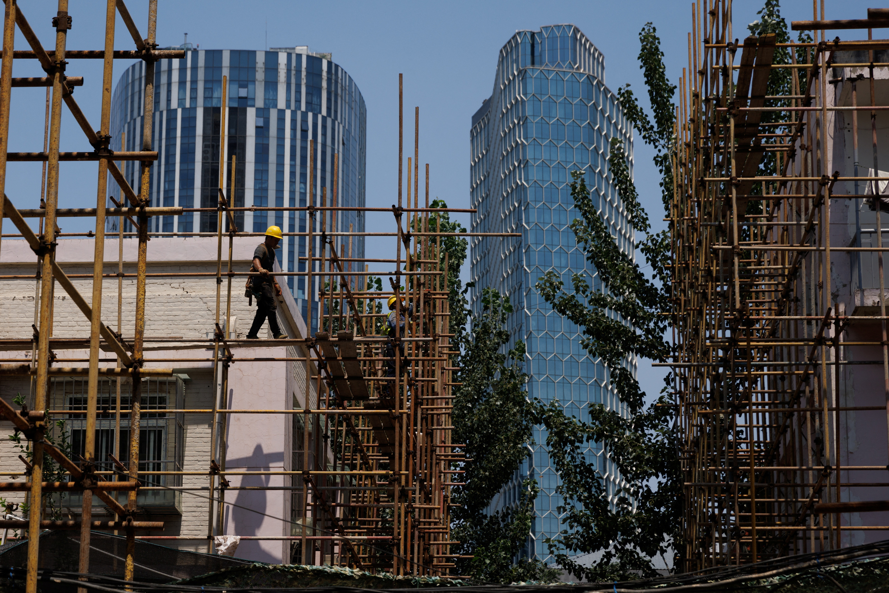 A worker walks on a scaffolding at a construction site of an apartment building under refurbishment in Beijing