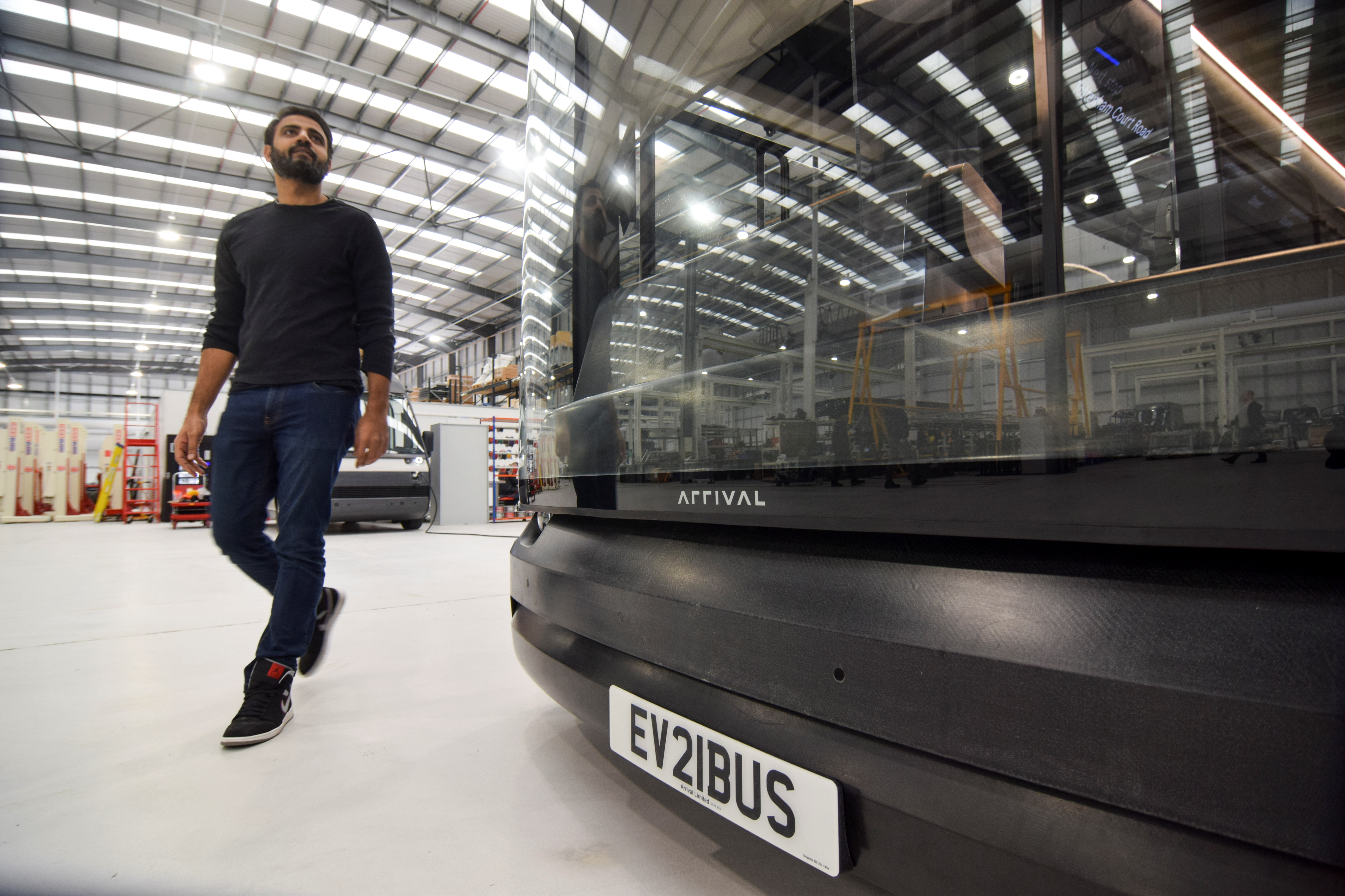 Avinash Rugoobur, president of electric van and bus maker Arrival, shows off the startup's pre-production electric bus model at the company's research and development centre in Banbury