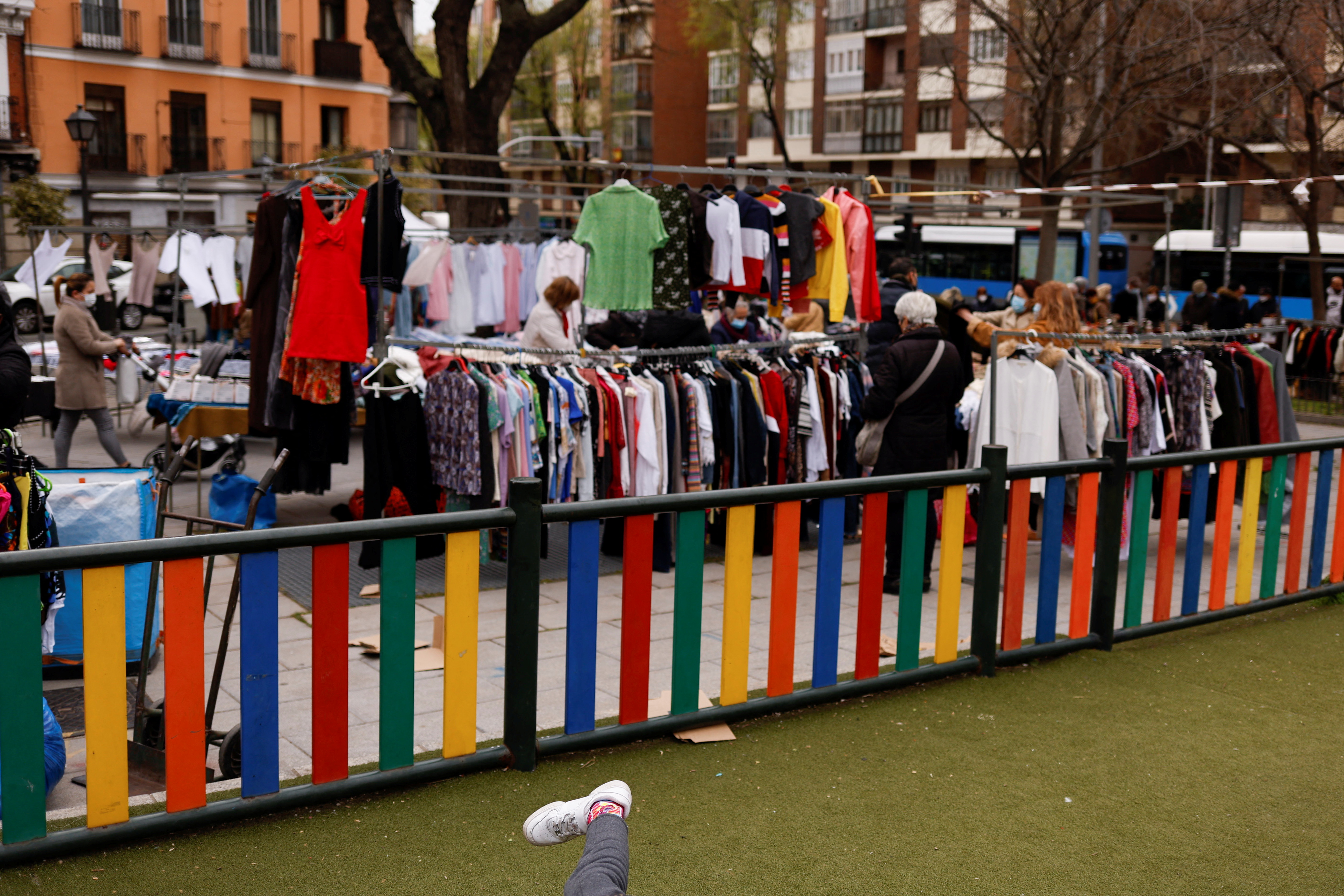 A child plays at a playground as people shop at a street market in Madrid