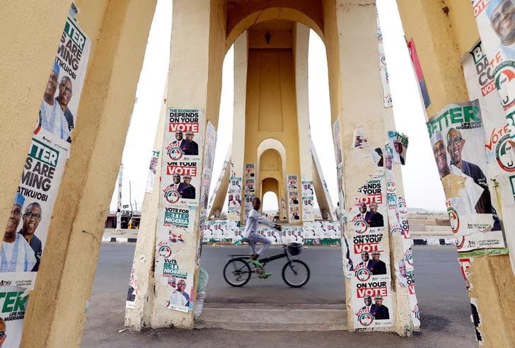 A boy rides a bicycle past a monument decorated with election posters depicting Nigeria's main opposition party presidential candidate Atiku Abubakar with his running mate, Peter Obi, in Yola