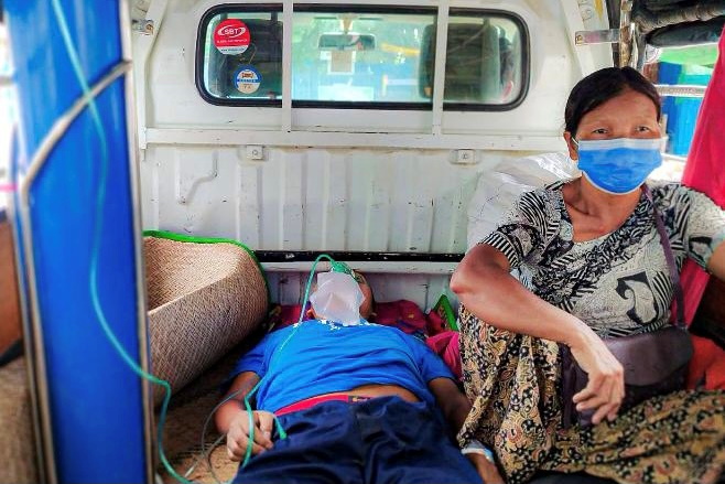 Relative sits with a coronavirus disease (COVID-19) patient being transported to hospital in the town of Kale, Sagaing Region, Myanmar