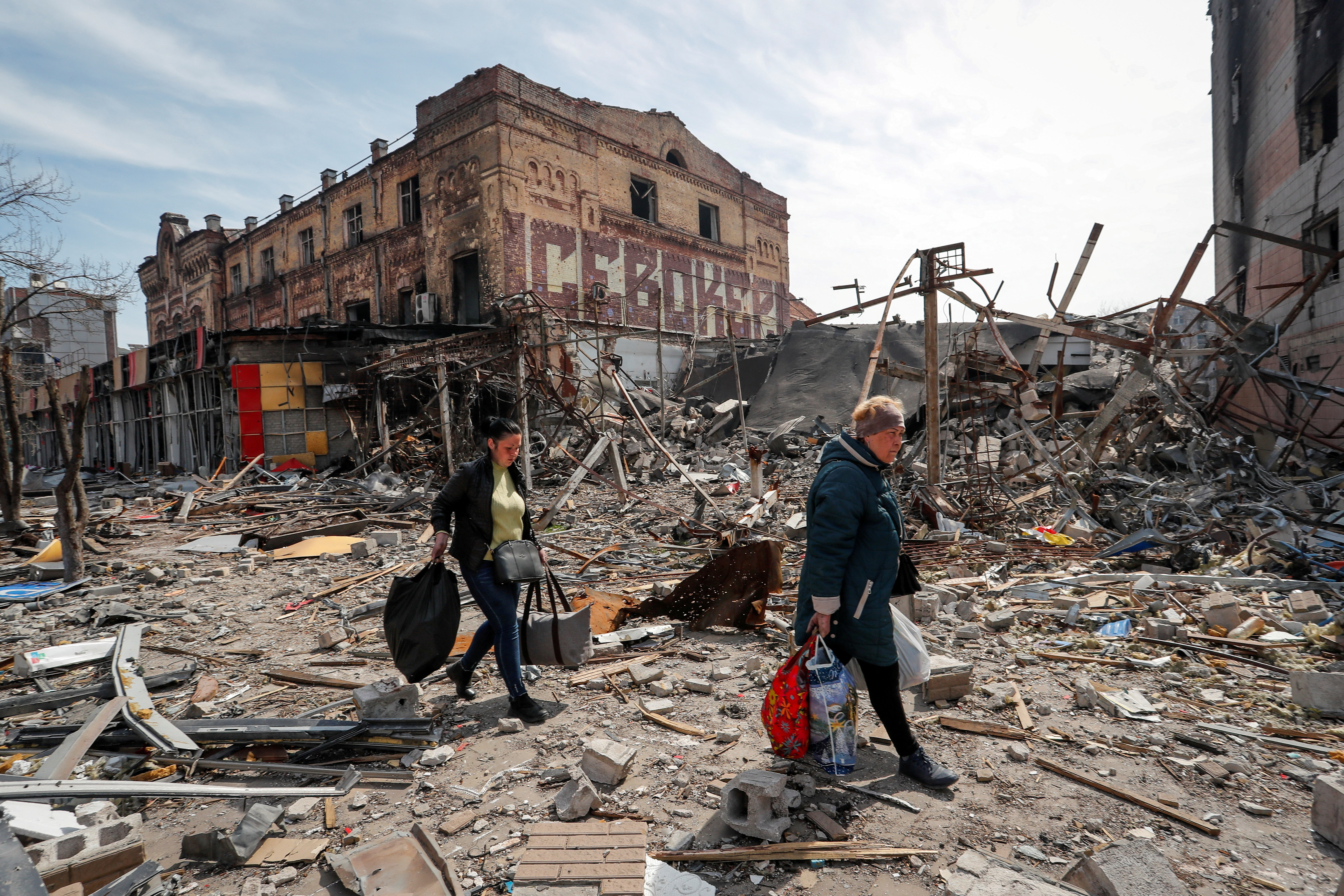 Residents carry their belongings near buildings destroyed in the course of the Ukraine-Russia conflict, in Mariupol
