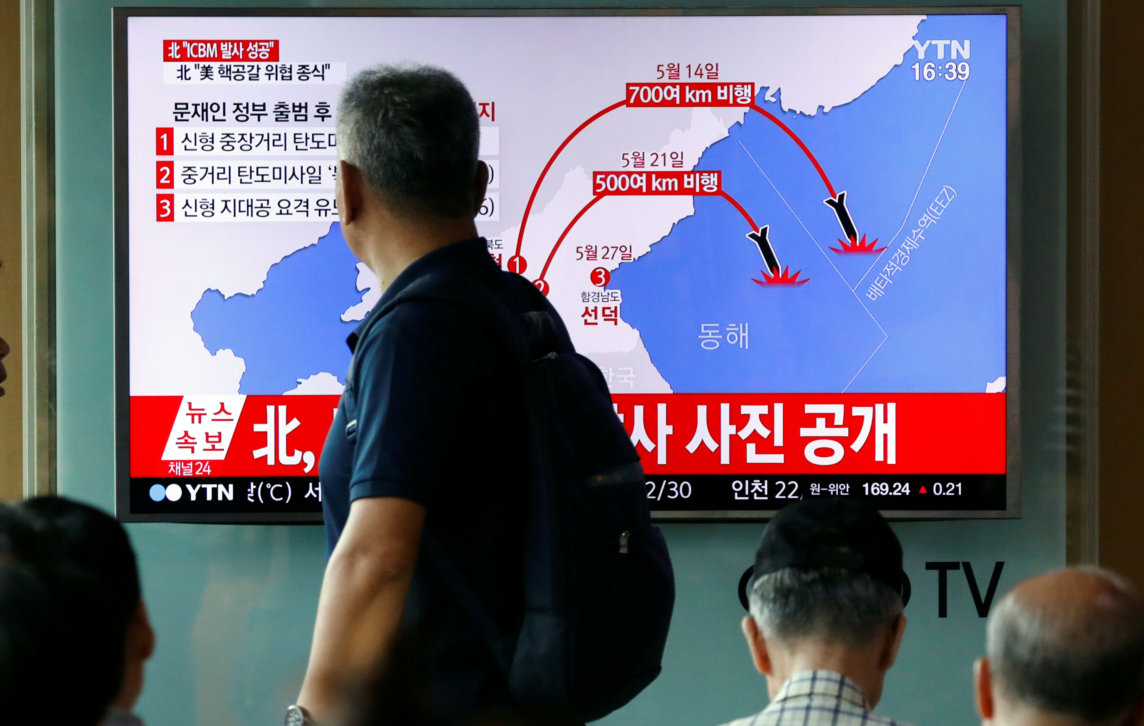 A man walks past a TV broadcasting a news report on North Korea's the Hwasong-14 missile, a new intercontinental ballistic missile at a railway station in Seoul