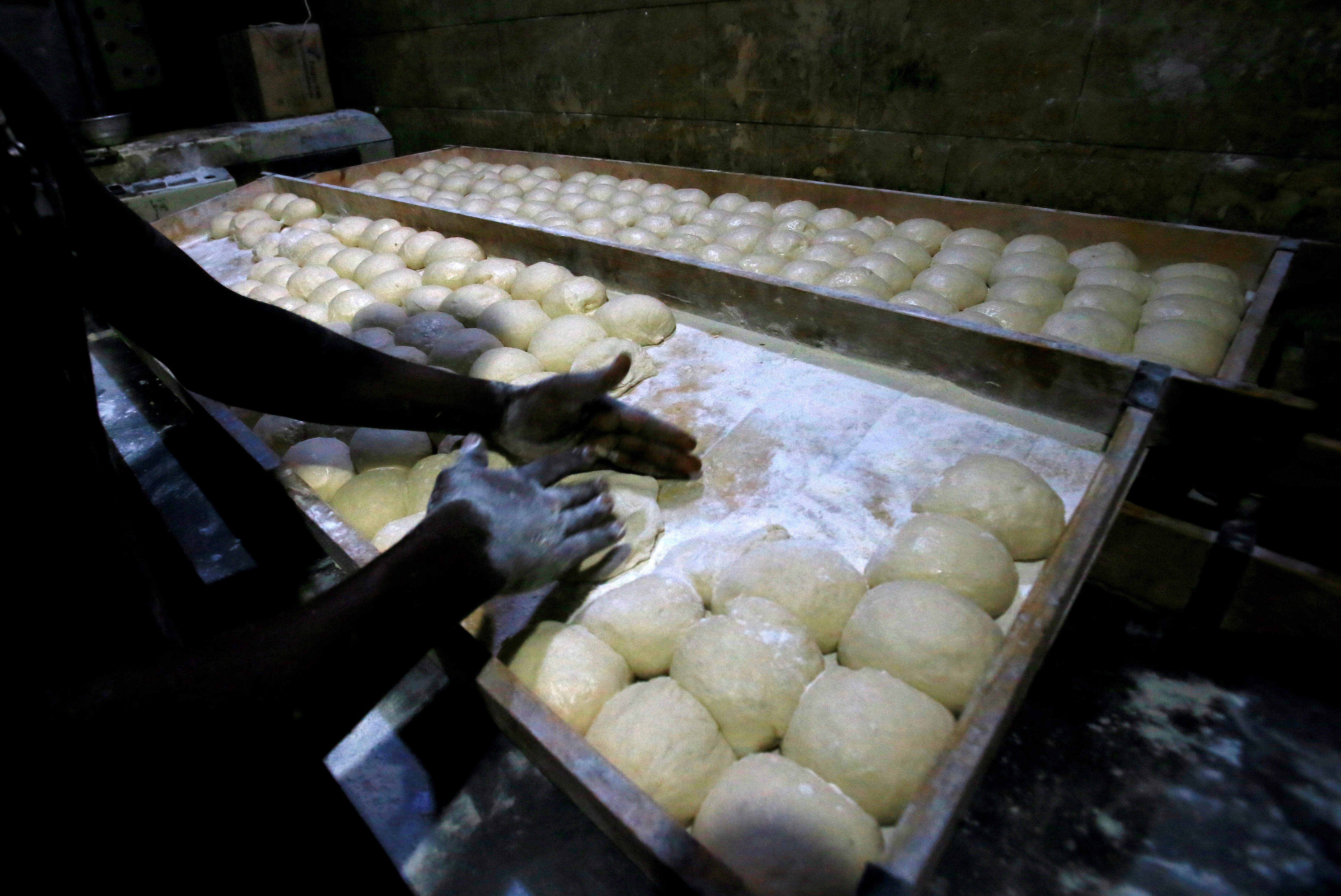 A worker prepares bread dough before baking in a traditional oven at a bakery in Khartoum