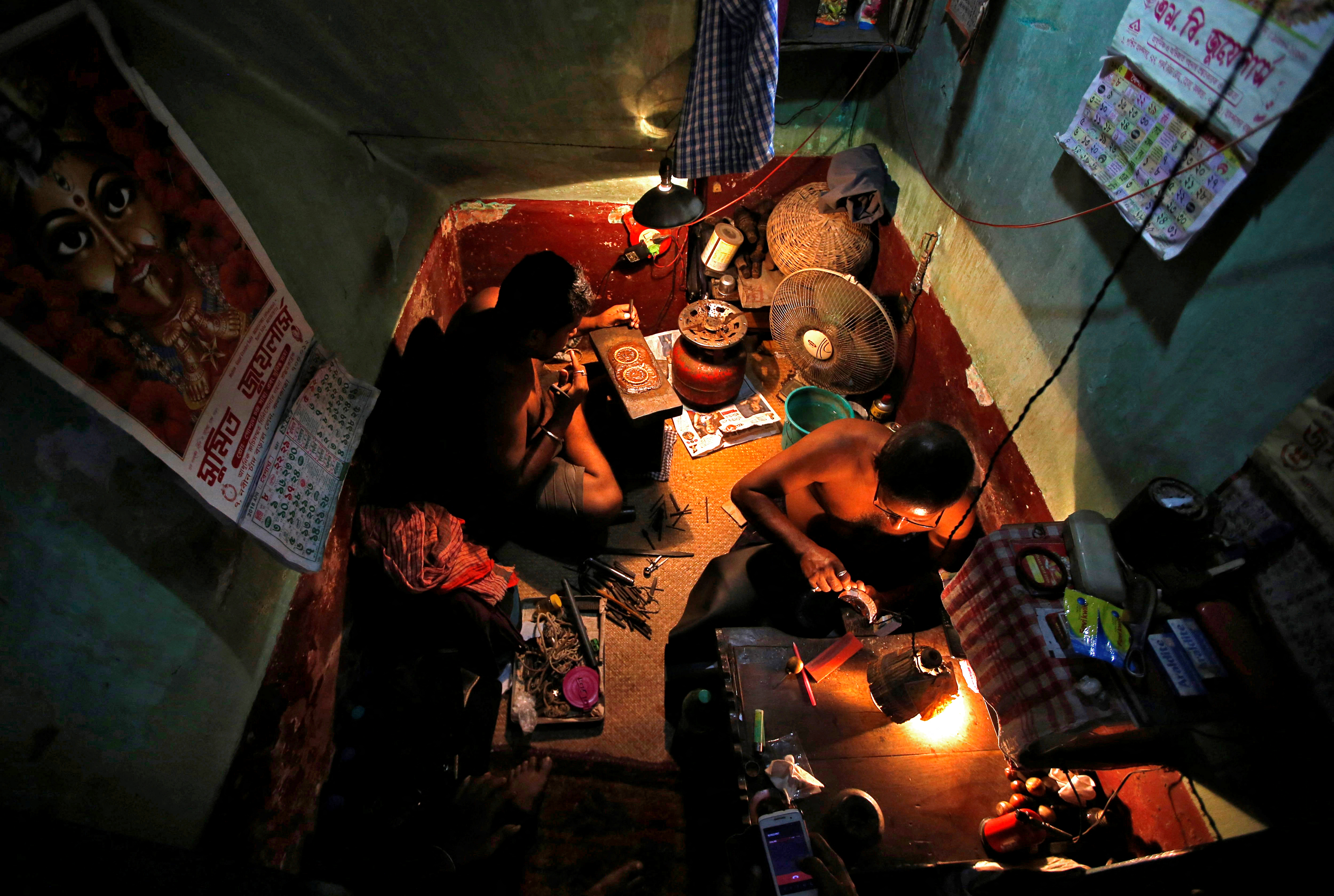 Goldsmiths work on gold ornaments at a workshop in Kolkata