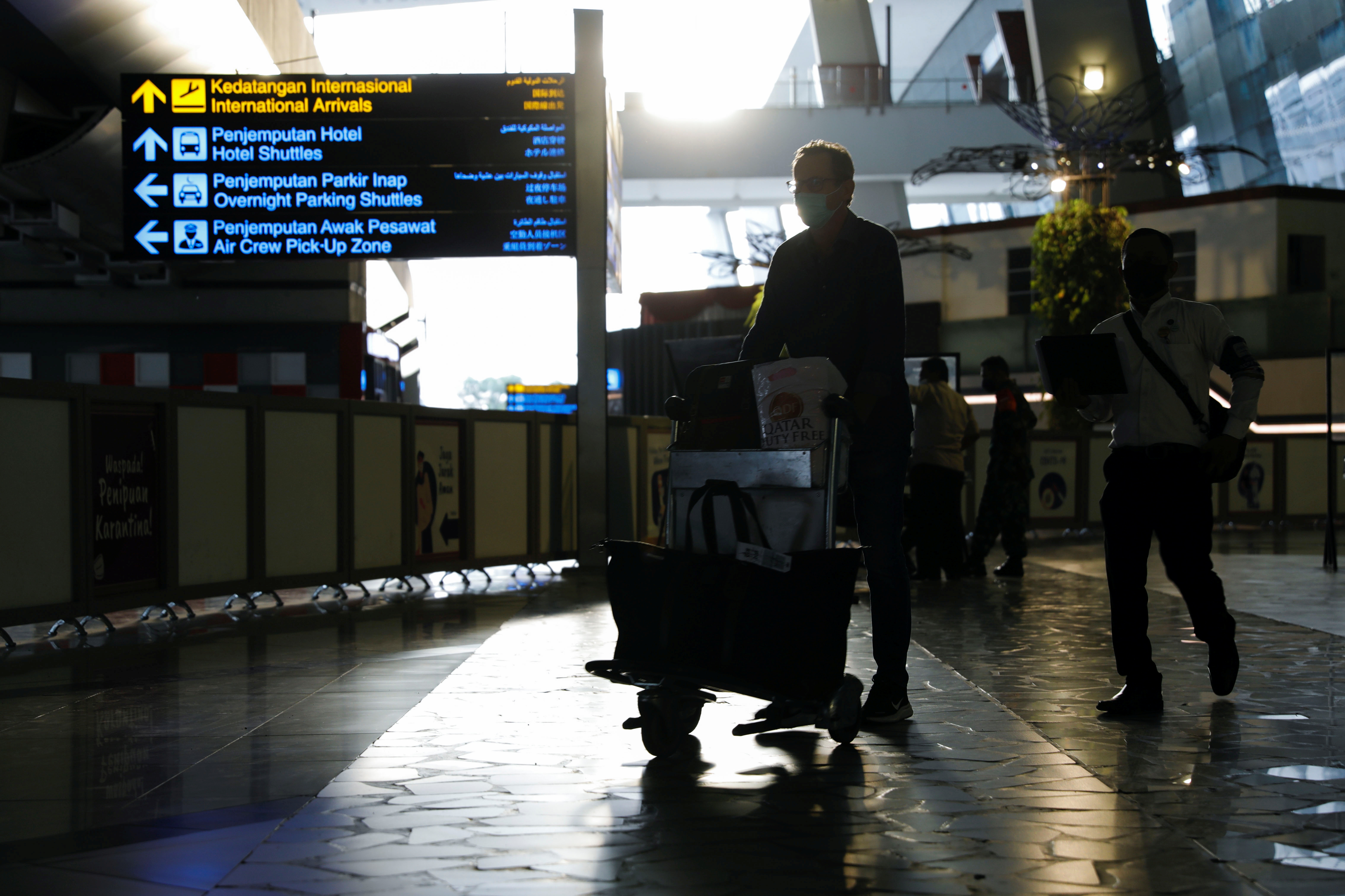A traveller wearing a protective mask carries his luggage at the arrival terminal of Soekarno Hatta International airport, as the country bans the arrival of travellers who have been in eight African countries to curb the spread of the new Omicron variant of the coronavirus, in Tangerang, near Jakarta, Indonesia, November 29, 2021. REUTERS/Willy Kurniawan/file photo