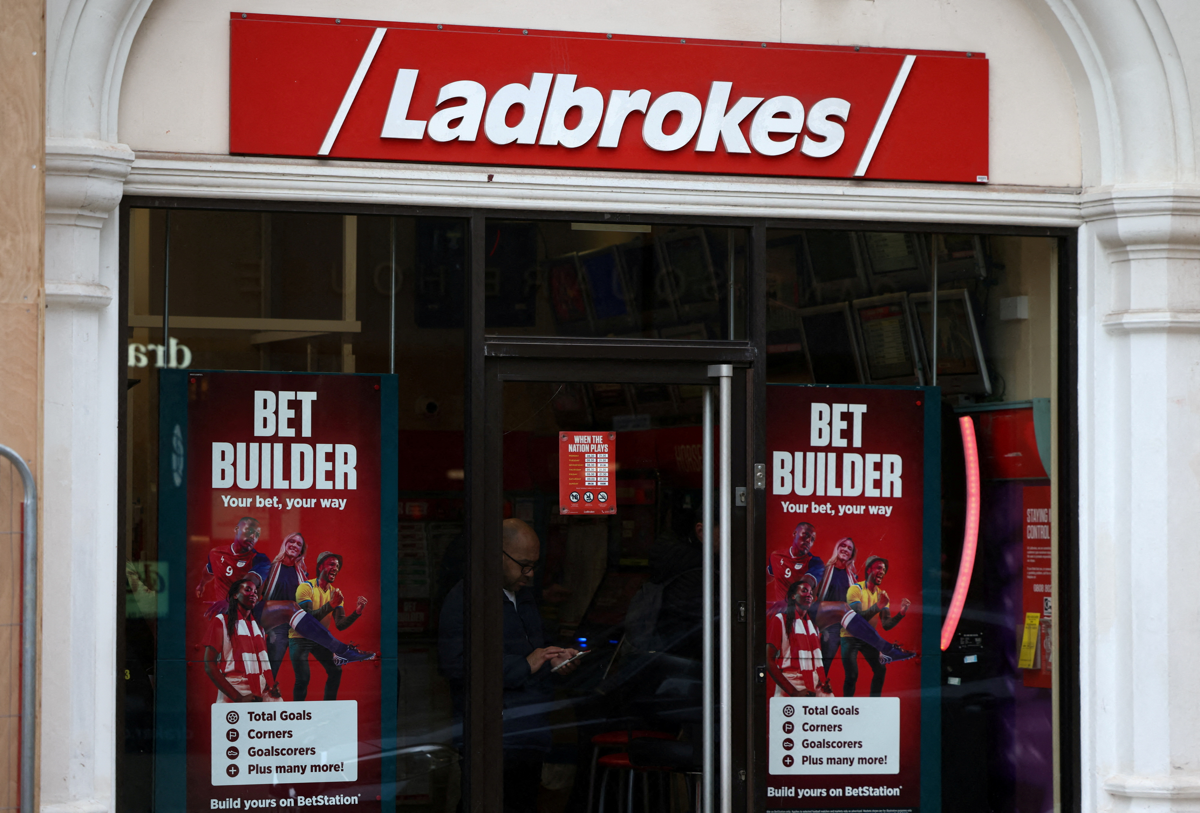 A person stands inside a Ladbrokes betting shop in London