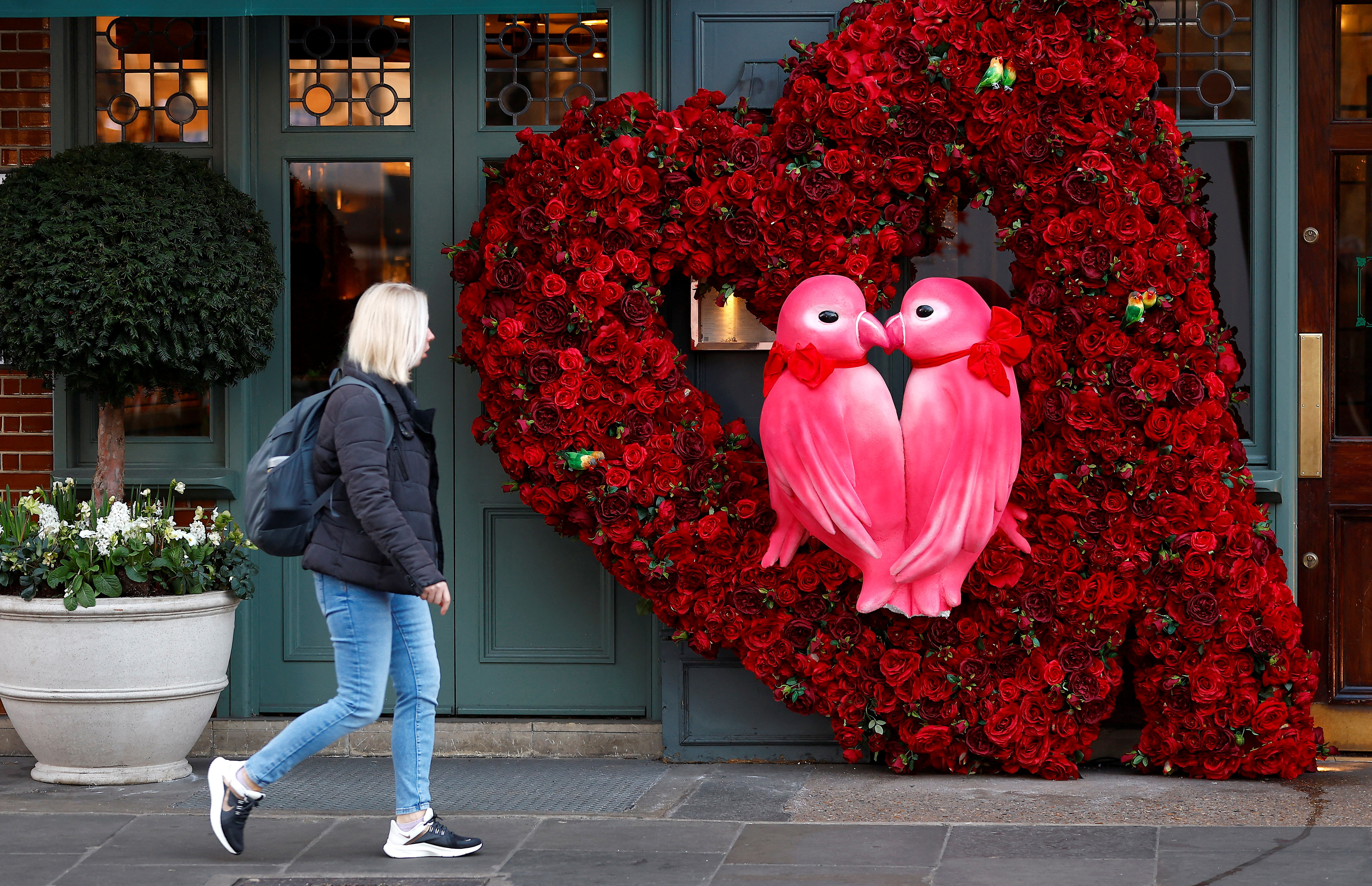 A woman walks past a Valentines Day floral display attached to the facade of a restaurant in London