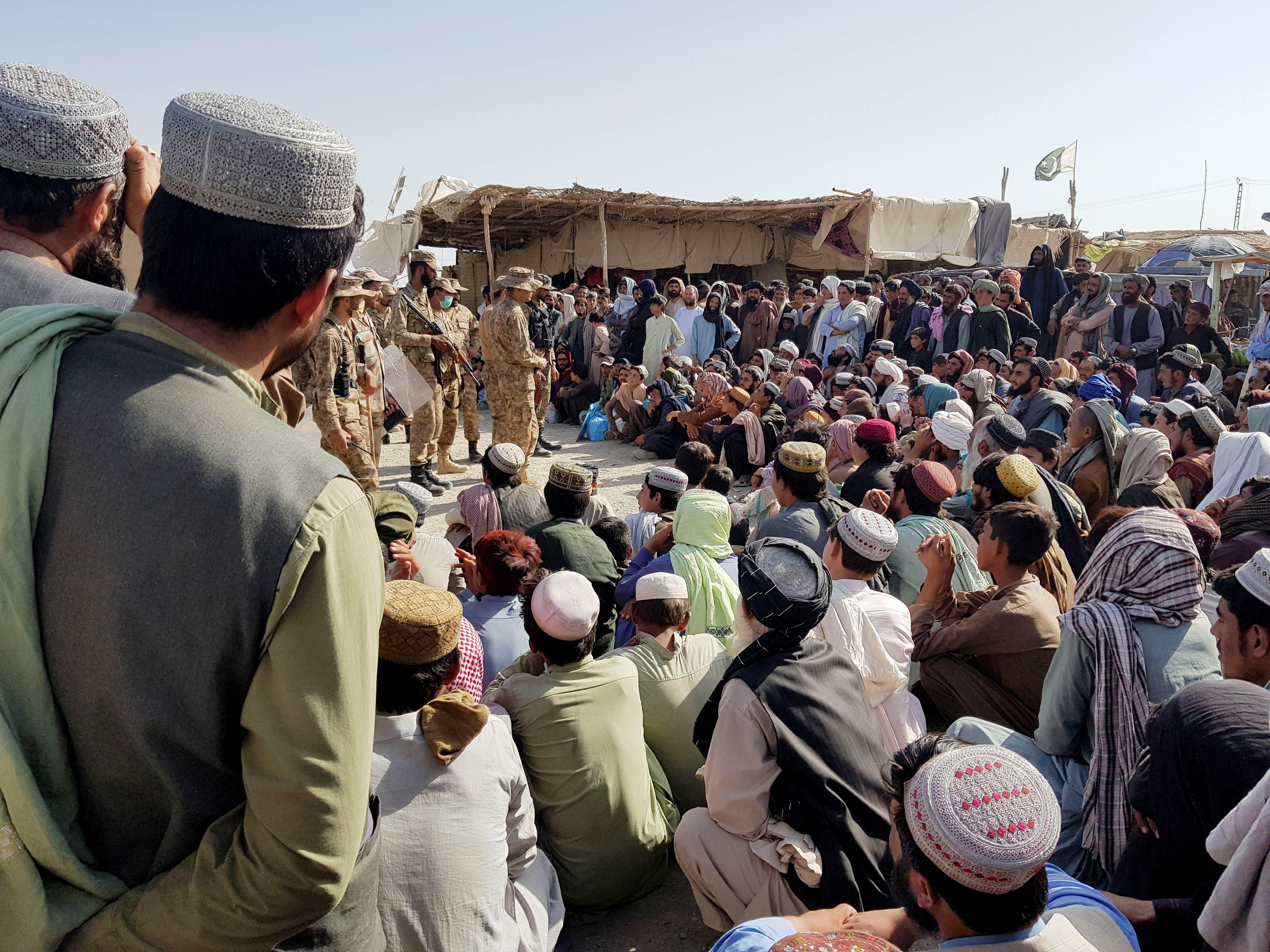 Pakistan's Army soldiers talk with people who gather to cross at the Friendship Gate crossing point in the Pakistan-Afghanistan border town of Chaman