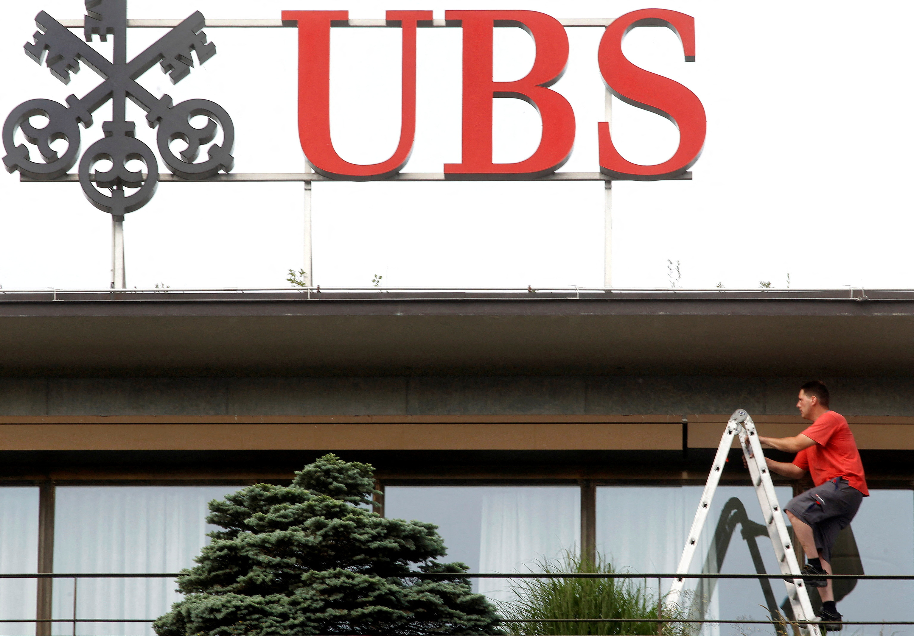 A worker climbs on a ladder under the logo of Swiss bank UBS at the company's headquarters in Zurich