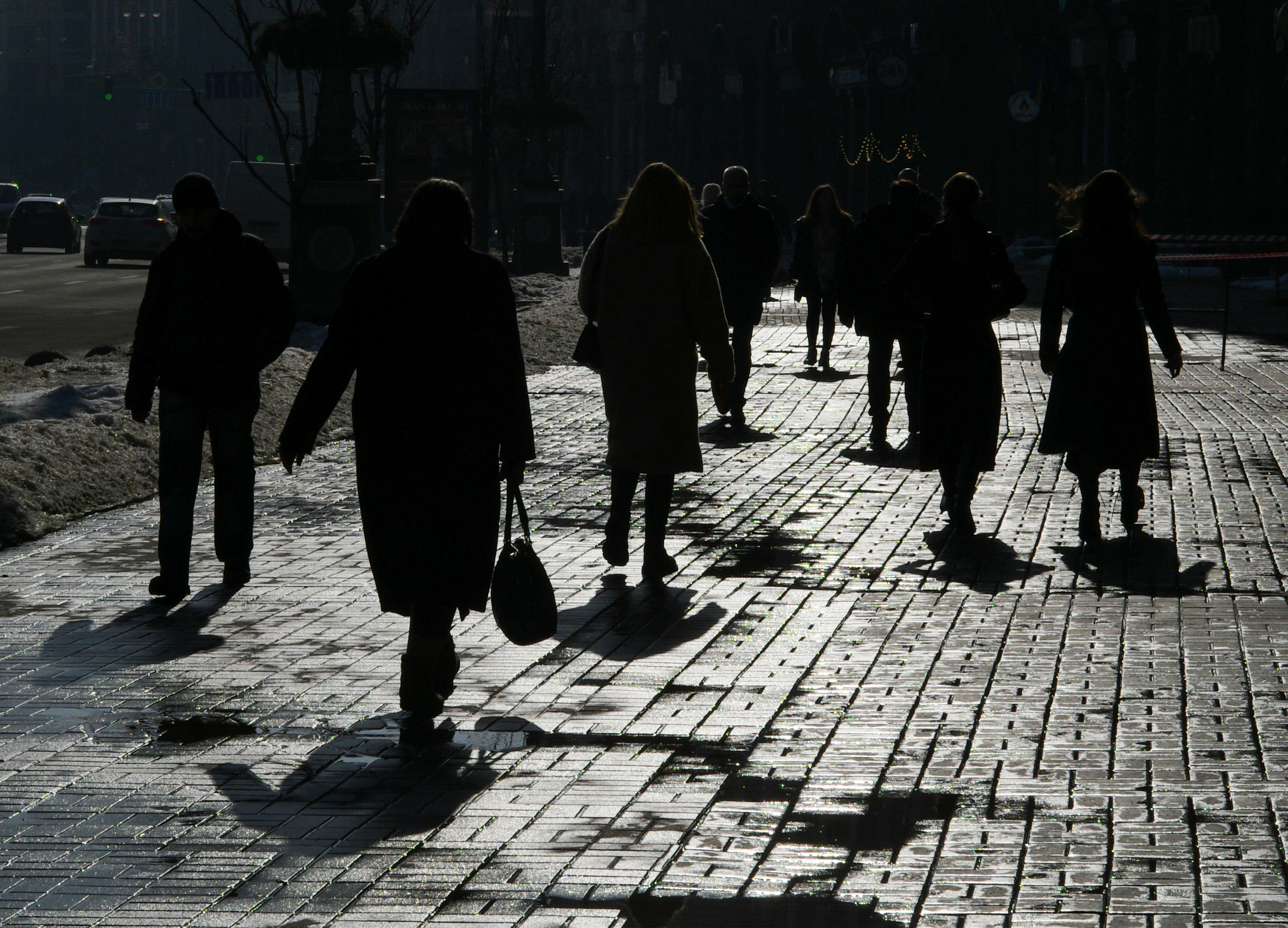 Pedestrians are silhouetted as they walk on a sunny day in central Kyiv