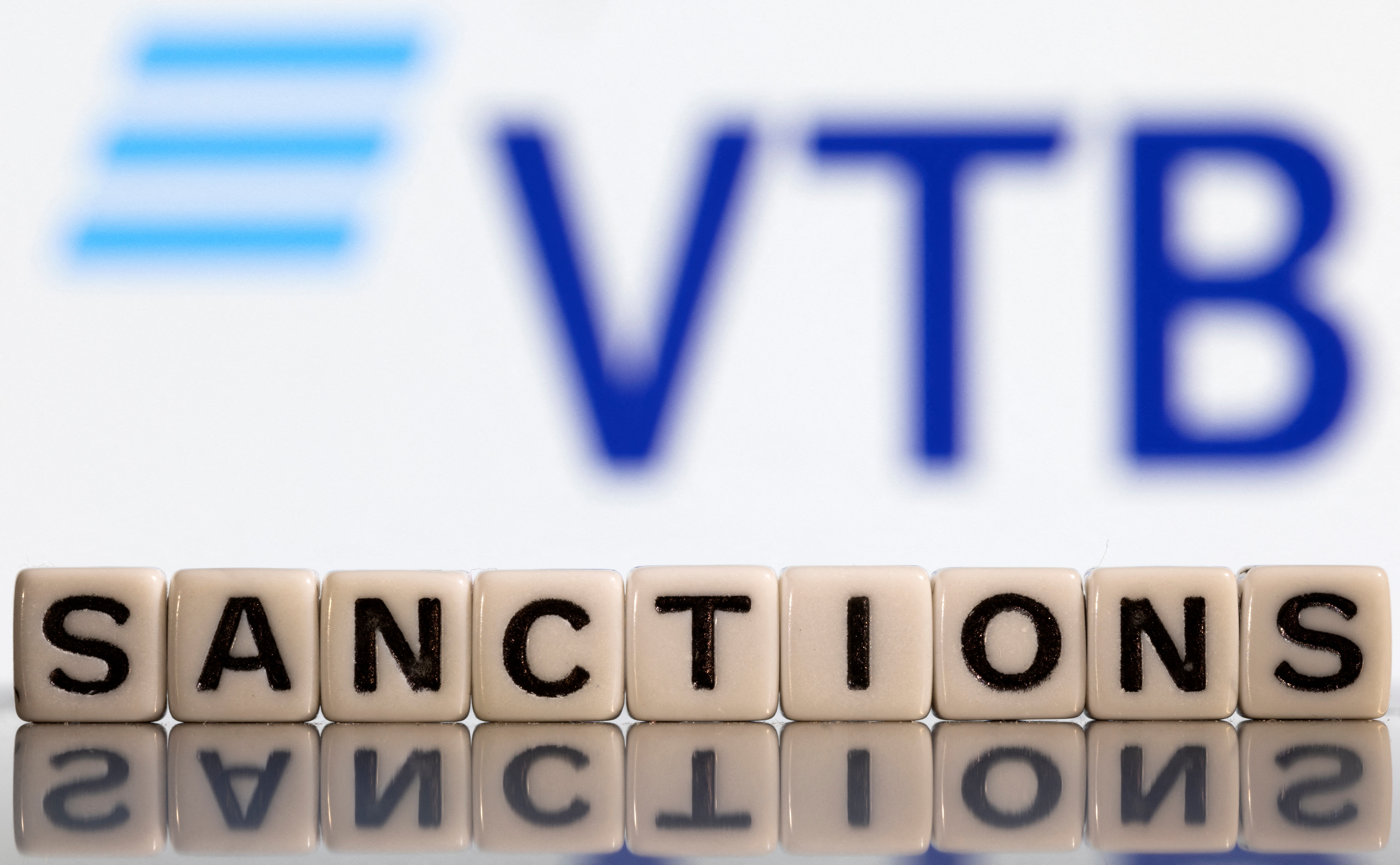 Illustration shows letters arranged to read "Sanctions" in front of VTB bank logo