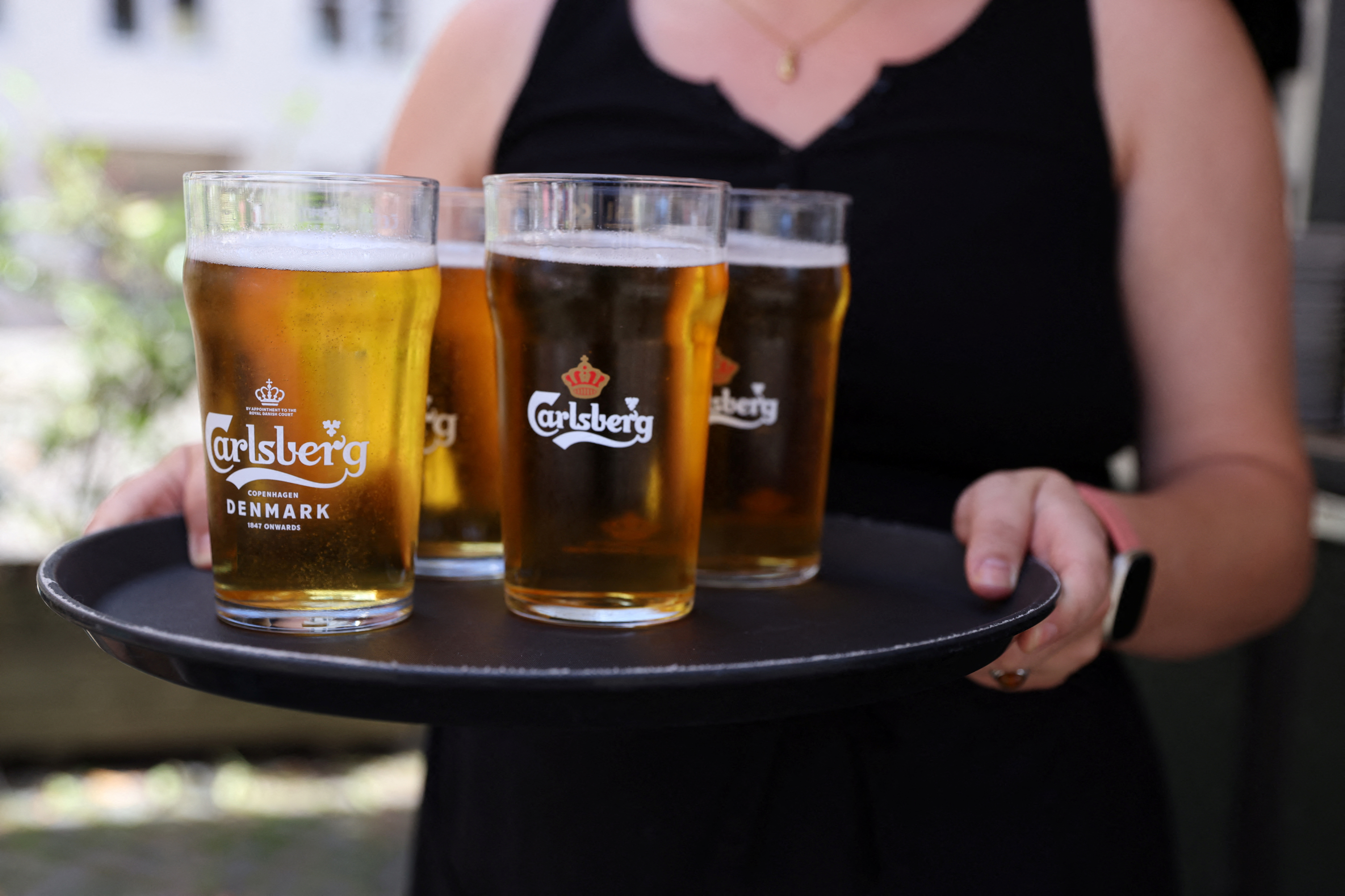 A bar worker carries a tray of Carlsberg beer in Copenhagen