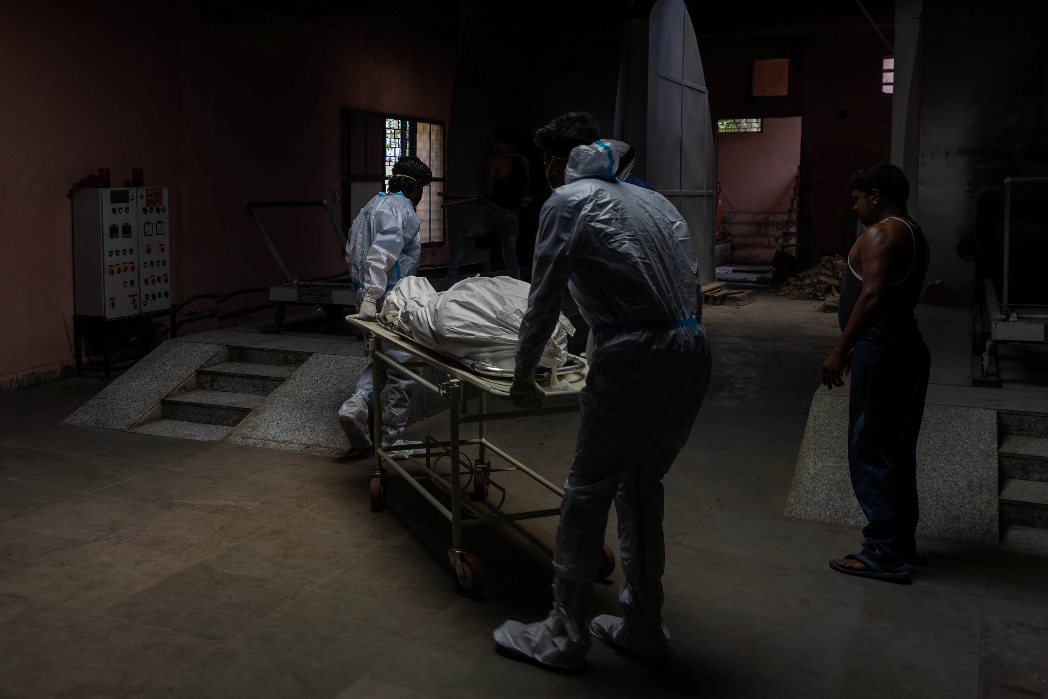 Health workers carry the body of a person, who died from complications related to the coronavirus disease (COVID-19), for cremation at a crematorium in New Delhi