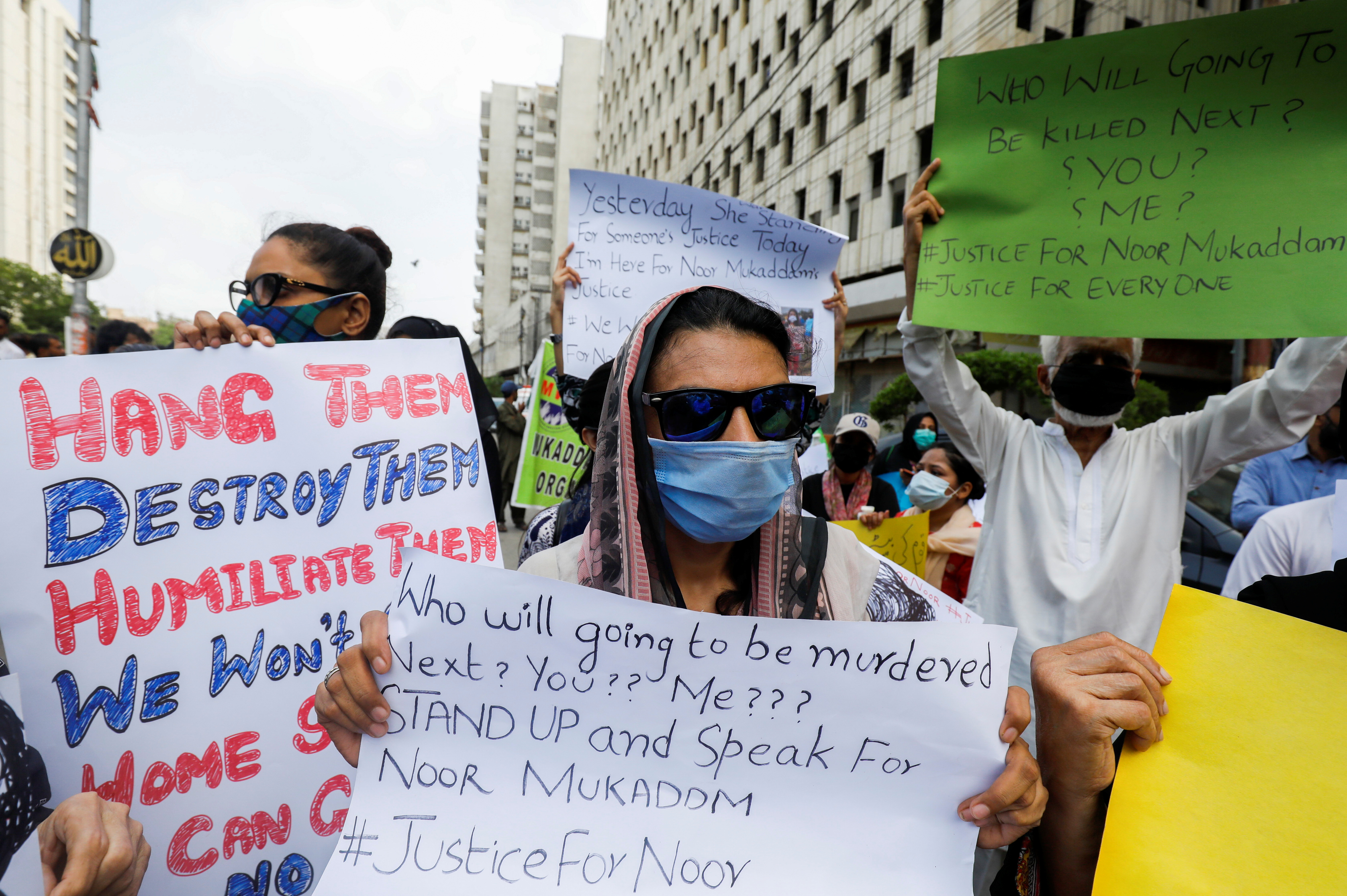 People carry signs to condemn the violence against women and girls during a protest in Karachi