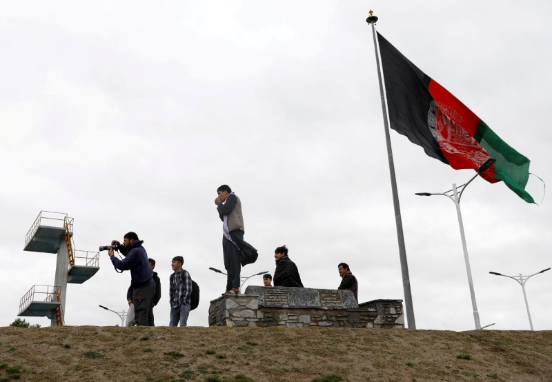 Youths take pictures next to Afghan flag in Kabul