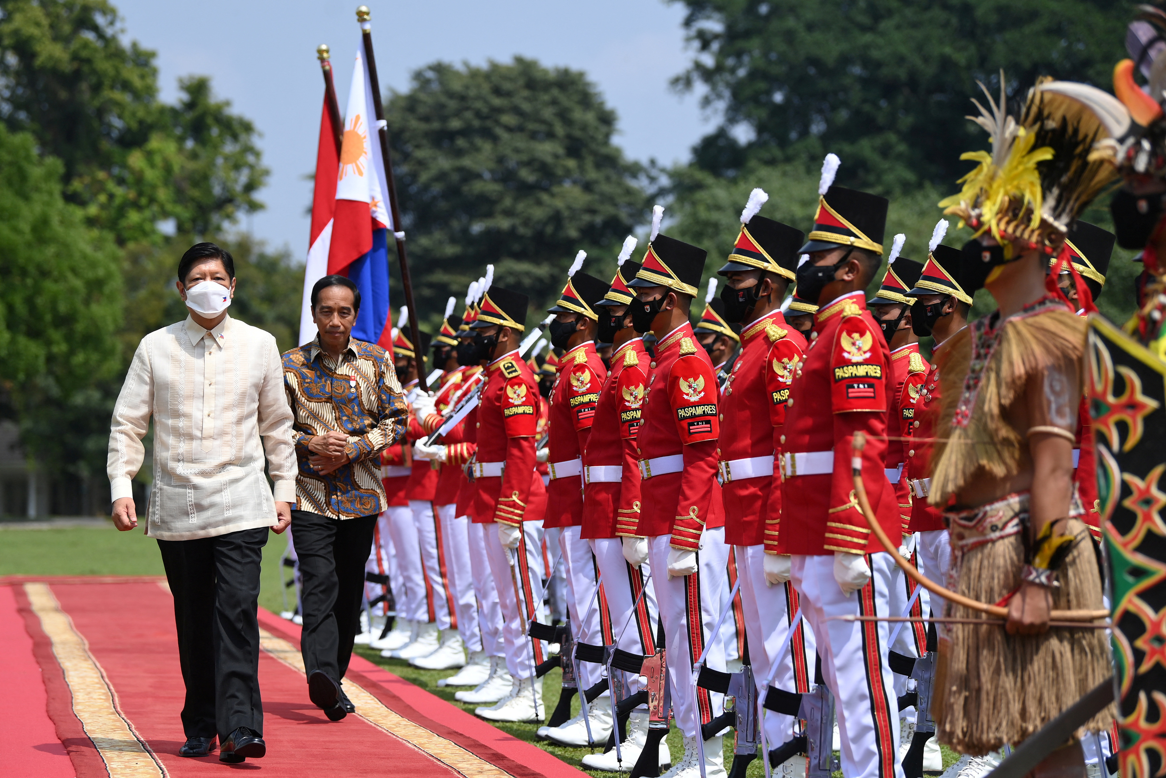 Indonesian President Joko Widodo walks with Philippine President Ferdinand "Bongbong" Marcos Jr. as they inspect the honour guards upon their arrival at the Presidential Palace in Bogor