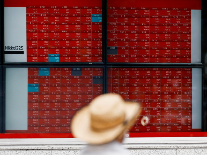 A man looks at an electronic board displaying the Nikkei stock average outside a brokerage in Tokyo