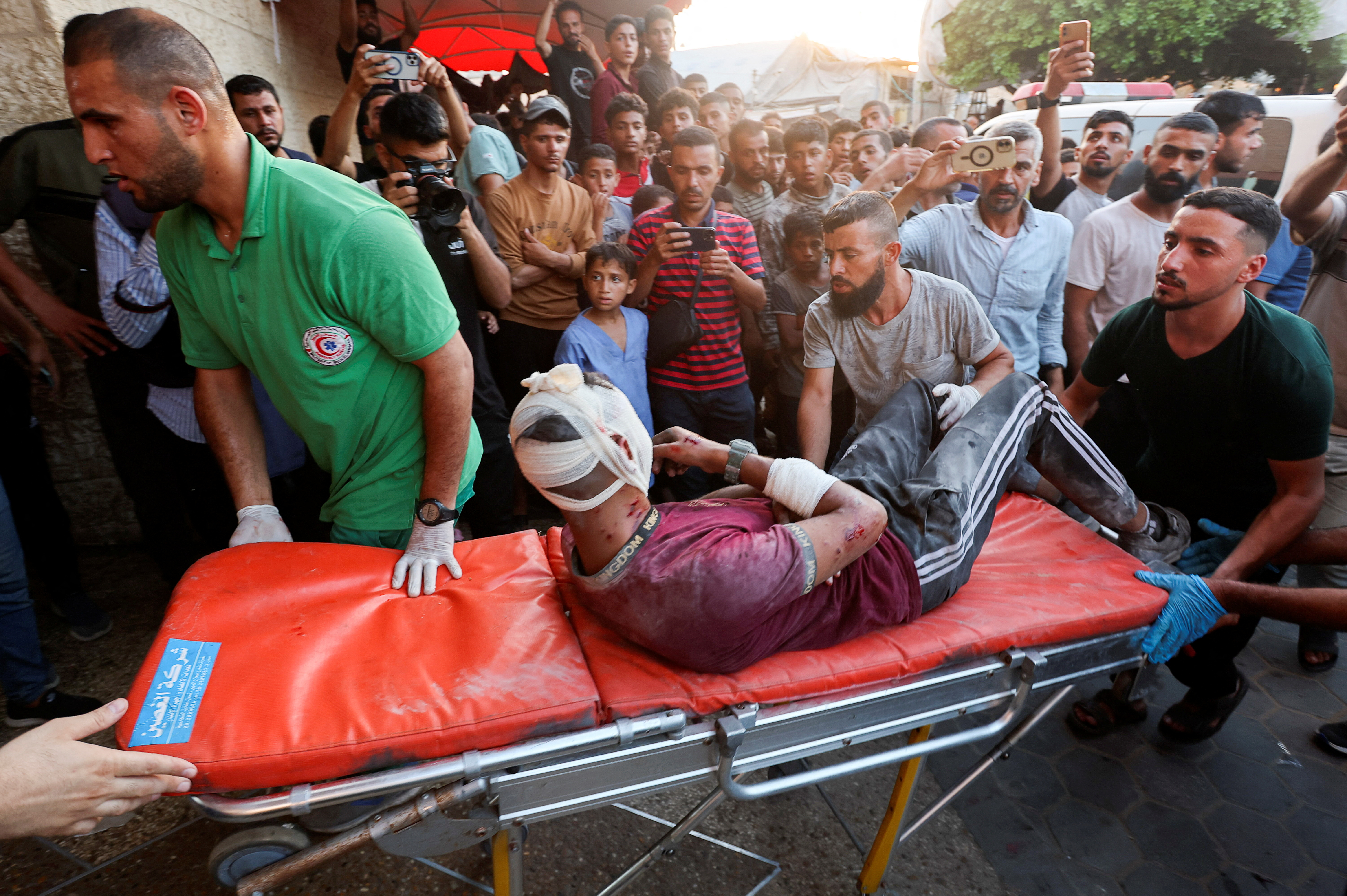 Medical workers tend to a Palestinian, who was wounded in an Israeli strike, in Deir Al-Balah