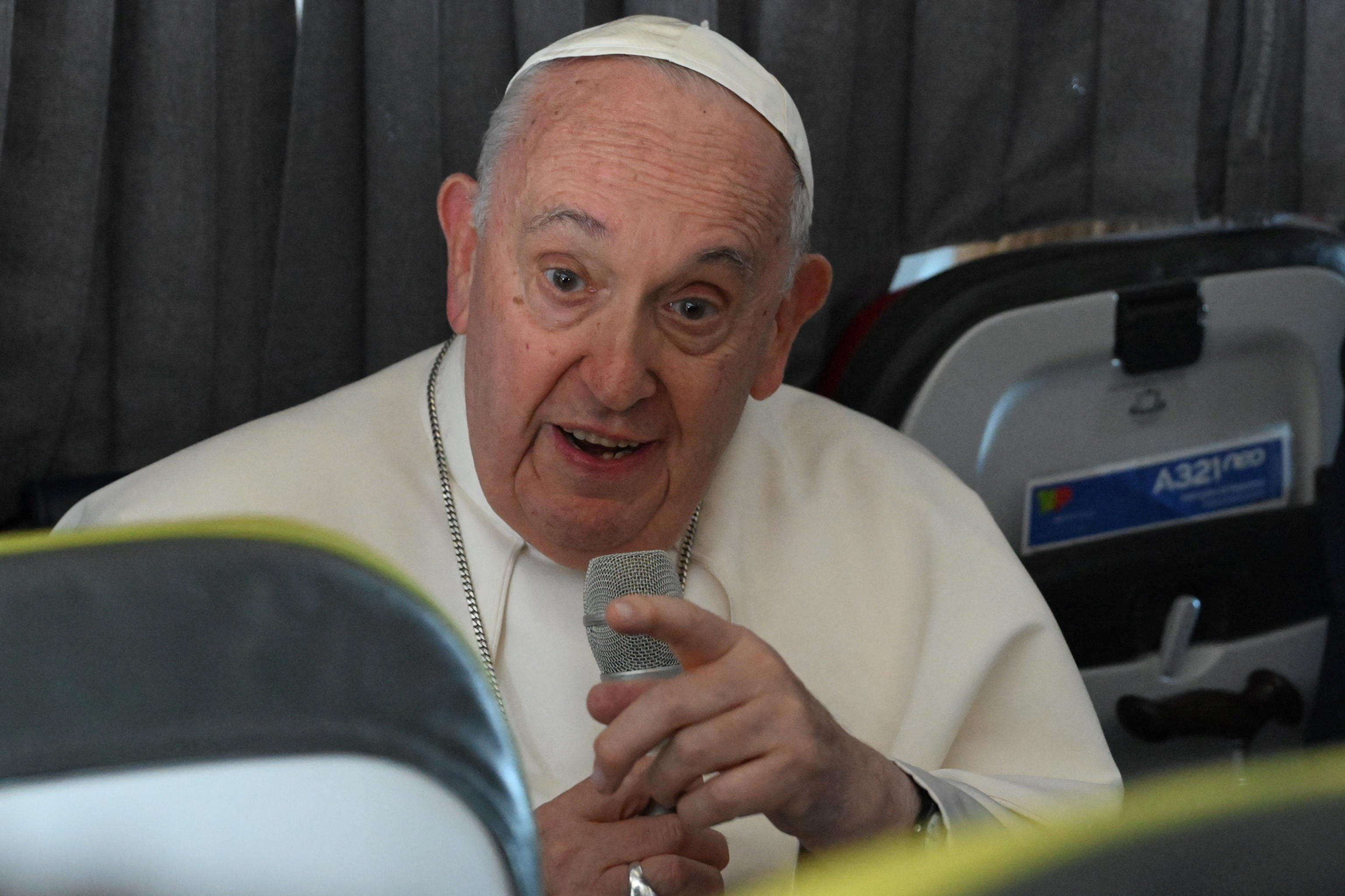 Pope Francis attends a press conference onboard a plane en route to Rome