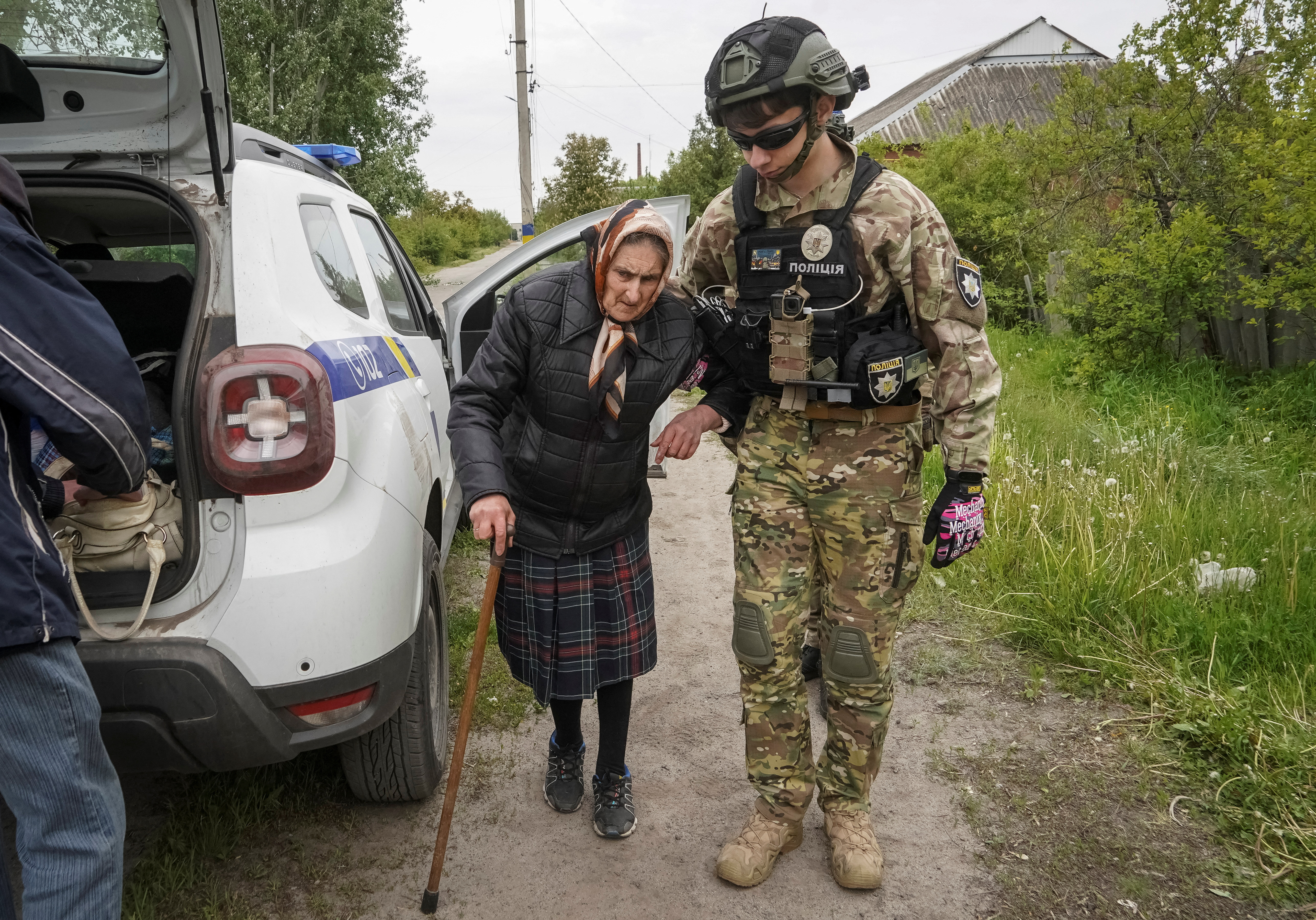 A police officer helps a local resident during an evacuation to Kharkiv due to Russian shelling in the town of Vovchansk