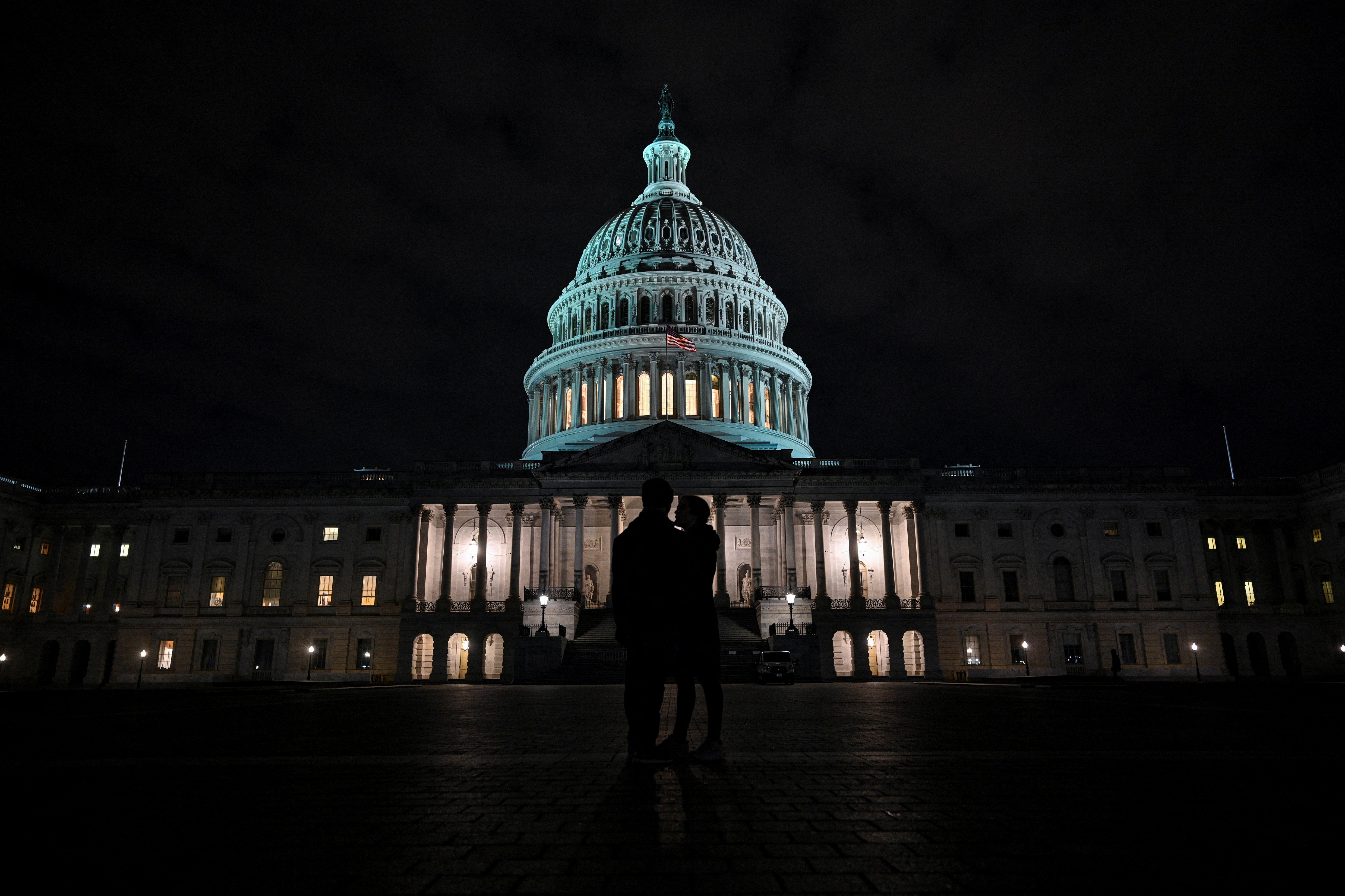 The moon is seen behind the dome of the U.S. Capitol building at night in Washington