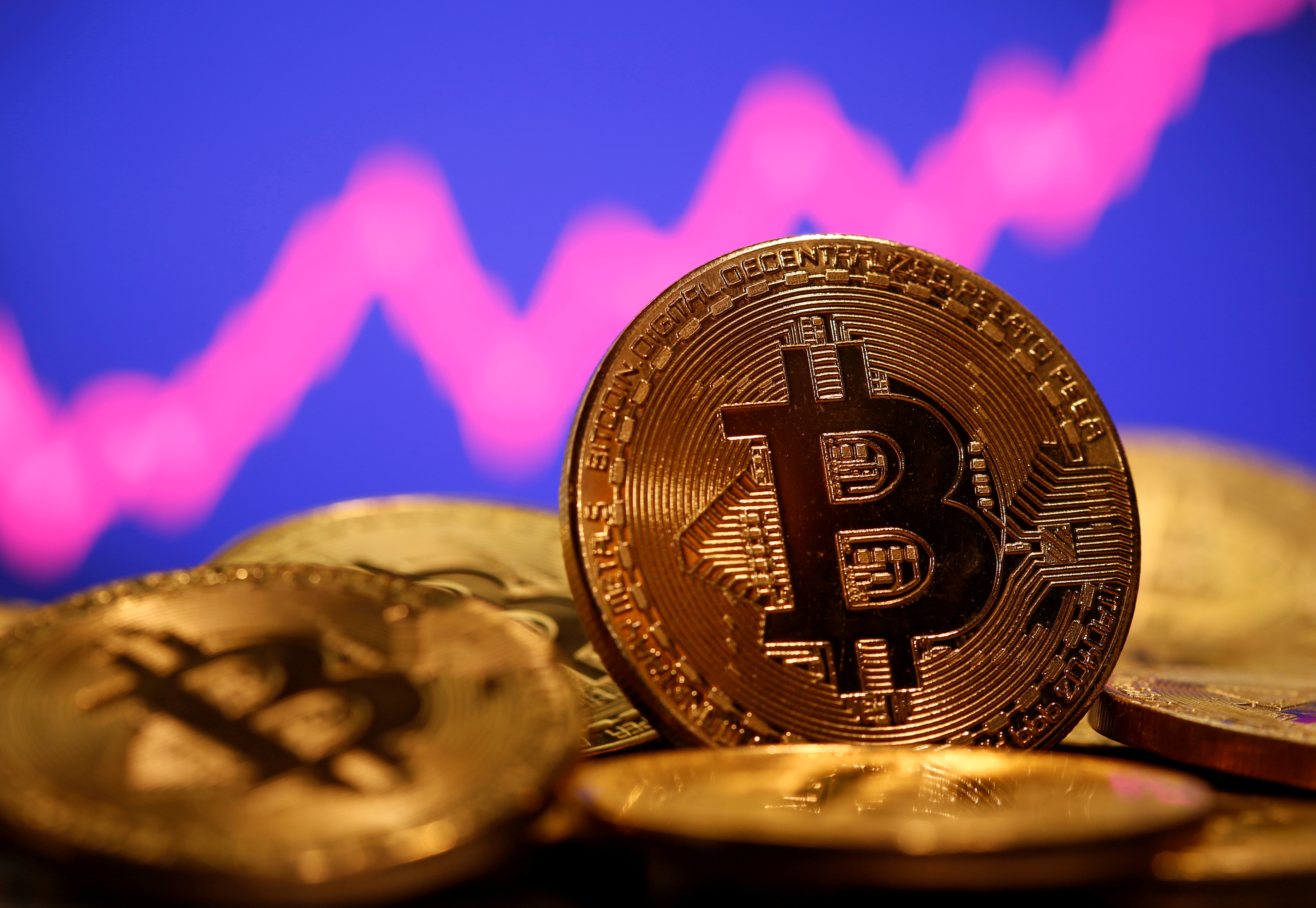 A representation of virtual currency Bitcoin is seen in front of a stock graph in this illustration taken