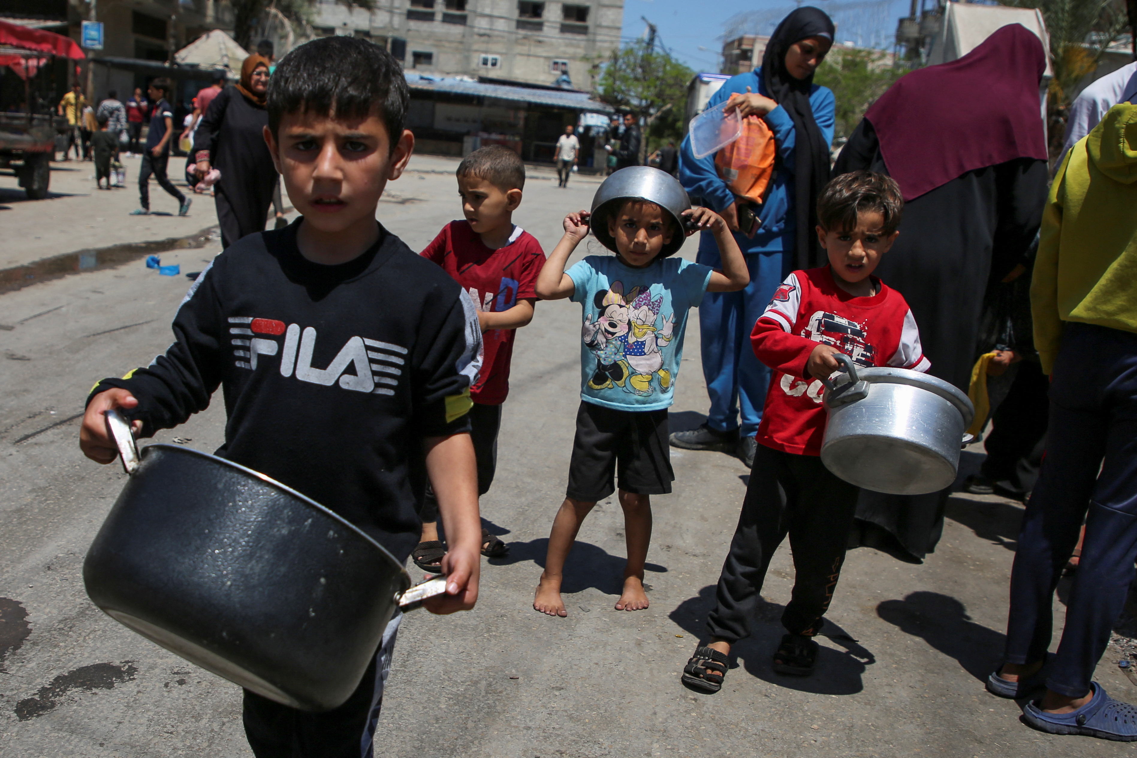 Palestinians wait to receive food cooked by a charity kitchen, in Rafah, in the southern Gaza Strip