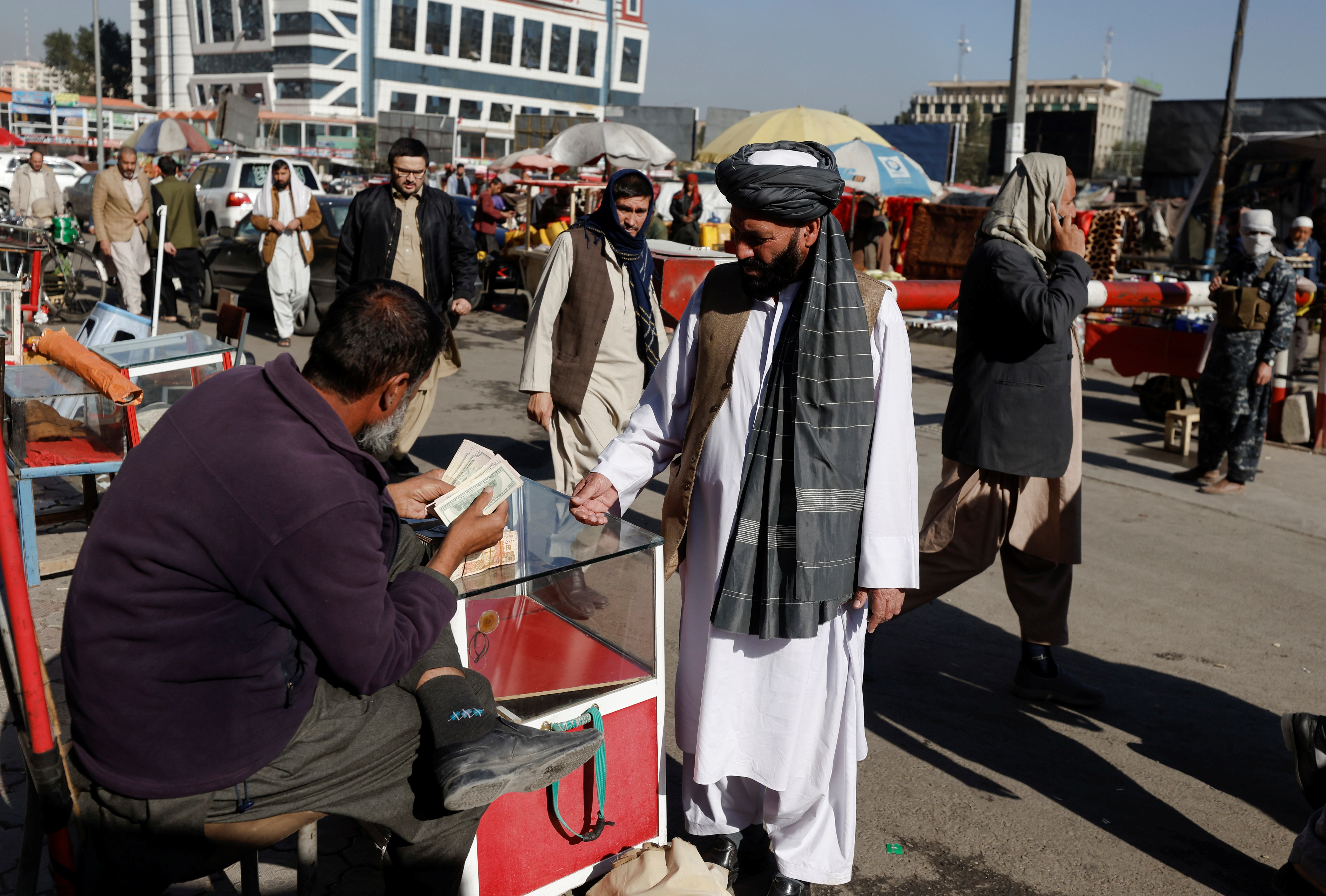 Afghan currency exchange dealer checks banknotes at the market in Kabul